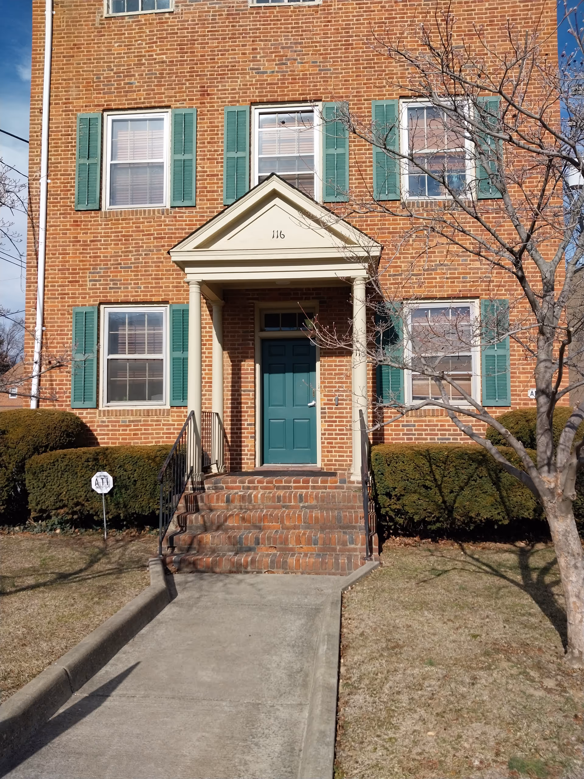 Brick building with green shutters and a front entrance