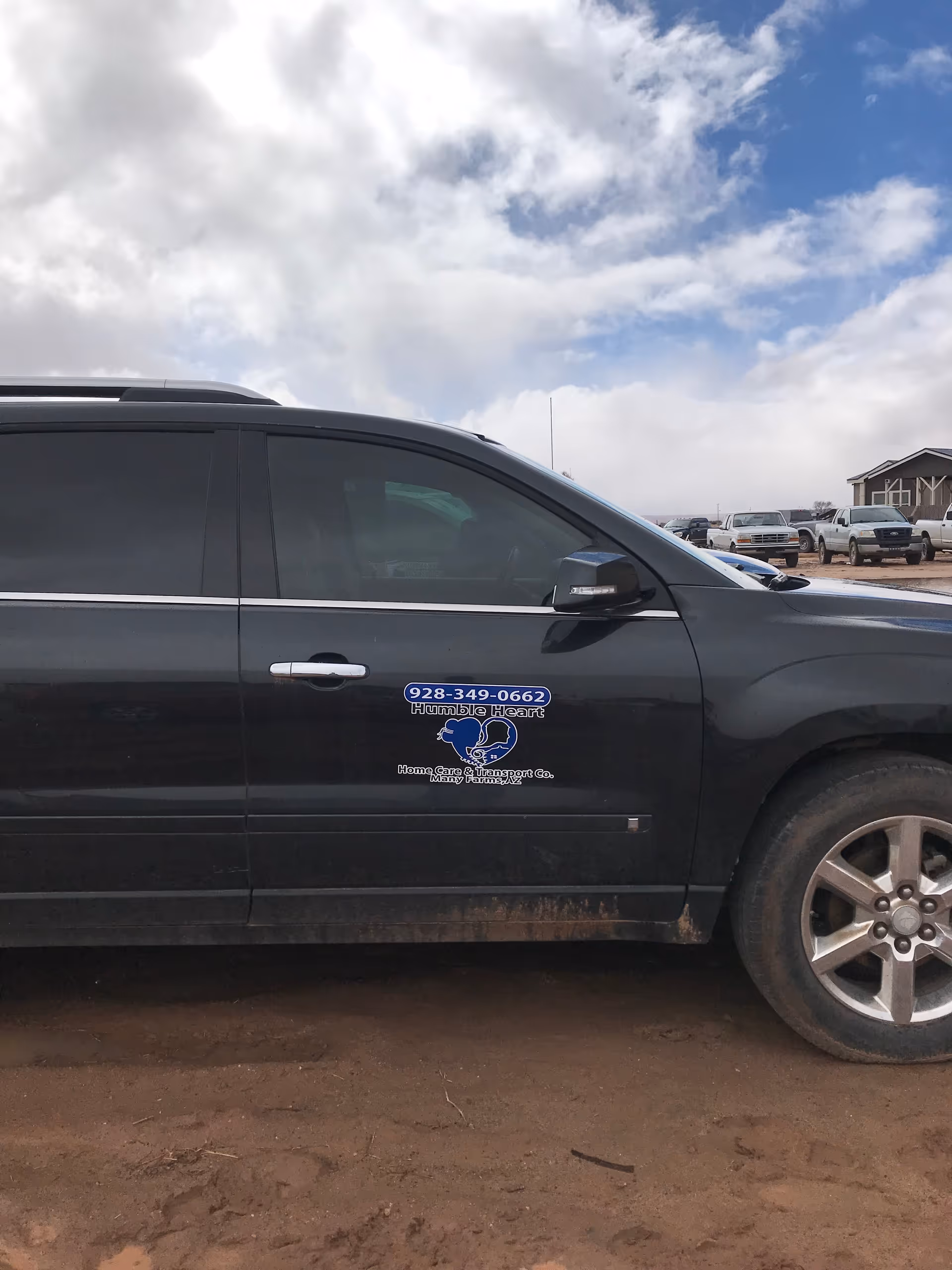 Black van with Humble Heart Home Care & Transport logo parked in a dirt lot.