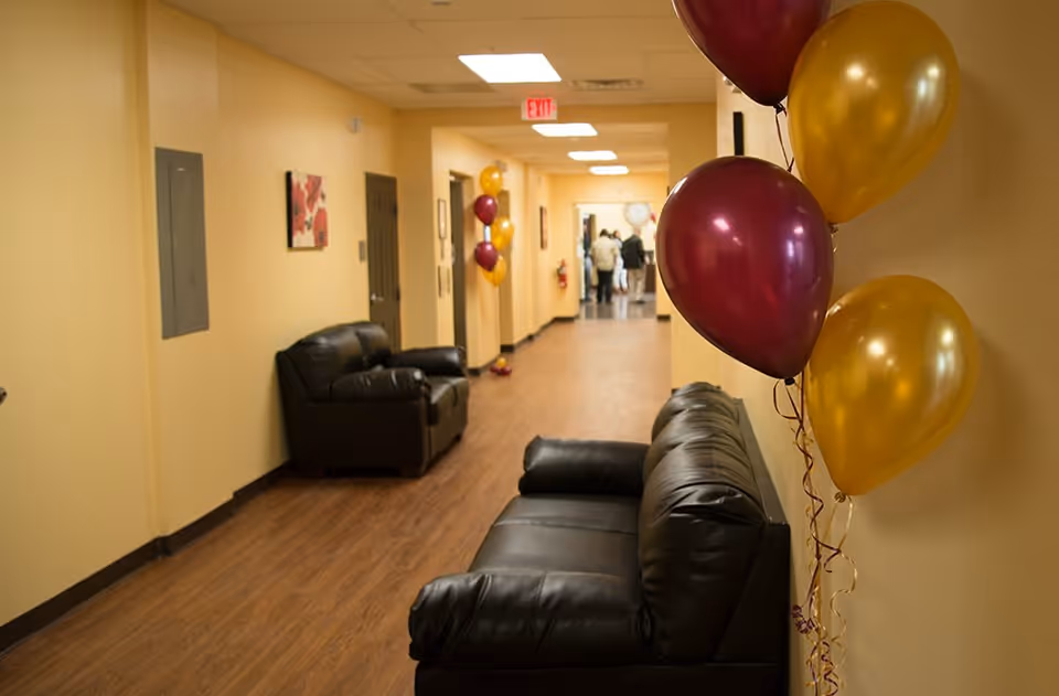 Long yellow hallway at Bethlehem Manor with black leather sofas and balloons.