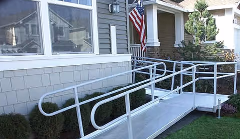 Exterior view of a senior living facility with a white wheelchair ramp and flag