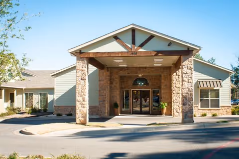 Front entrance of Heartis Longview senior living facility with stone columns and covered entryway.
