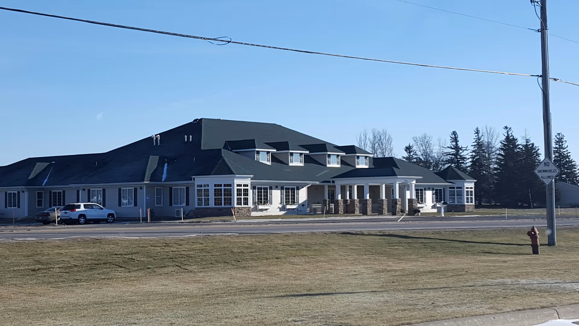Exterior view of a long senior living center with a dark roof and white columns.