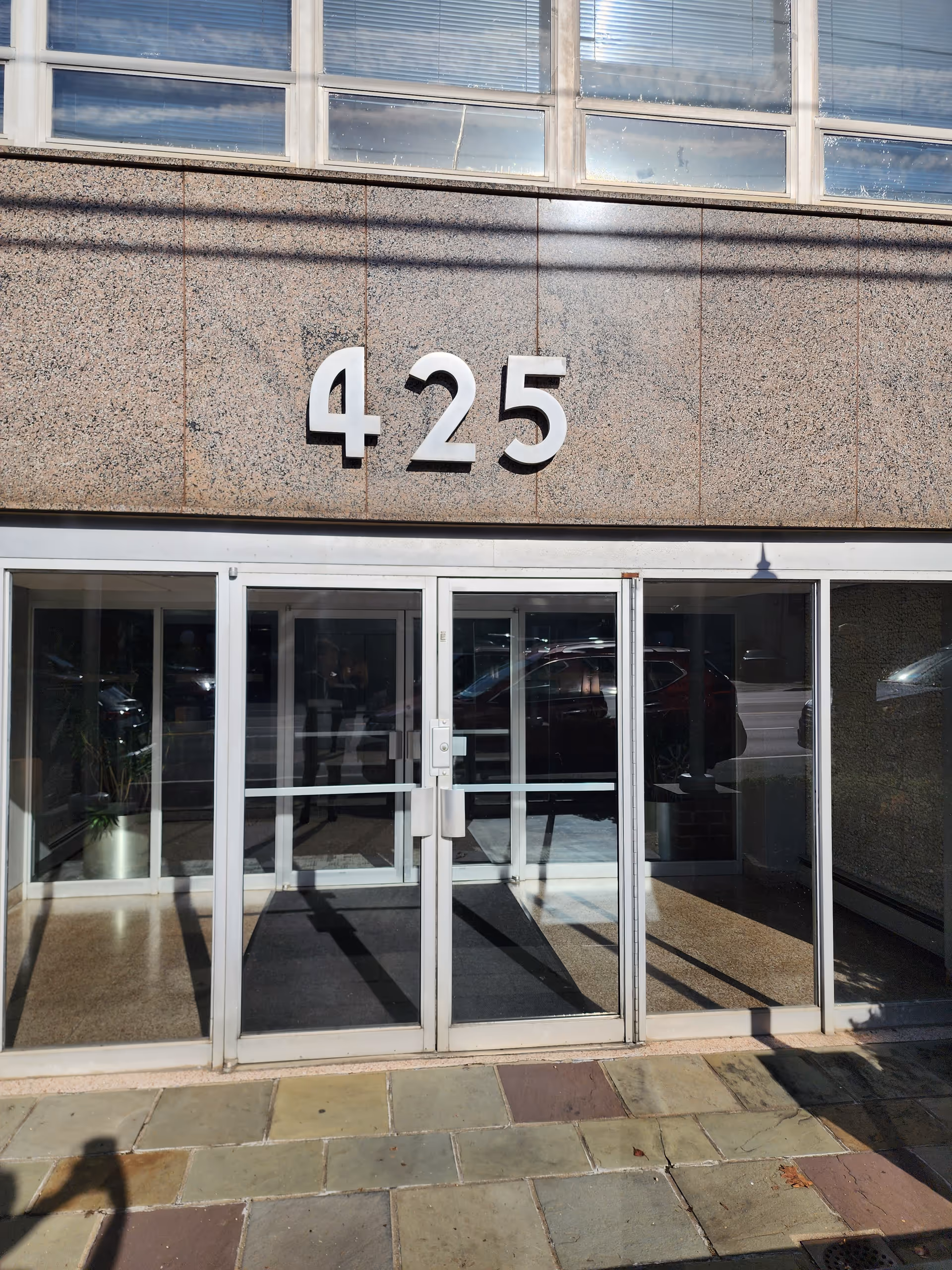 Glass double doors with the number 425 displayed on a stone facade.