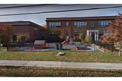 Exterior view of Marvin senior living facility with a fenced courtyard, outdoor seating, and playground equipment.