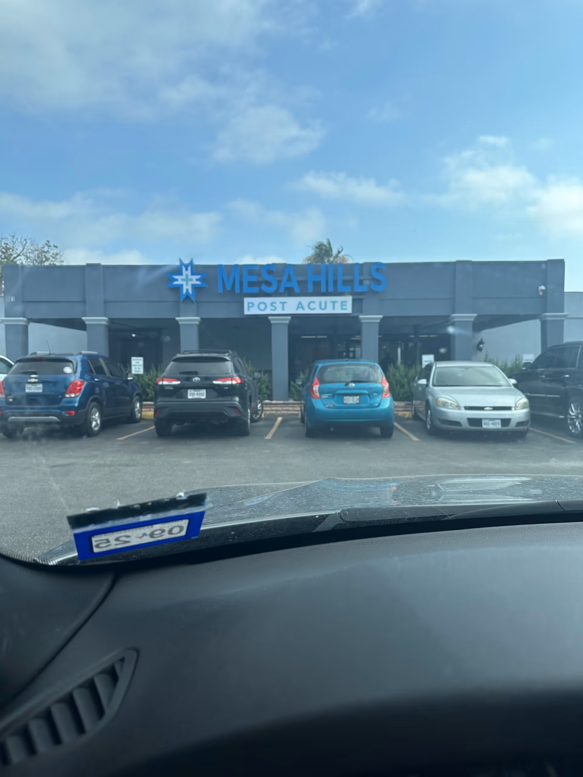 Front view of a medical facility with a row of parked cars.