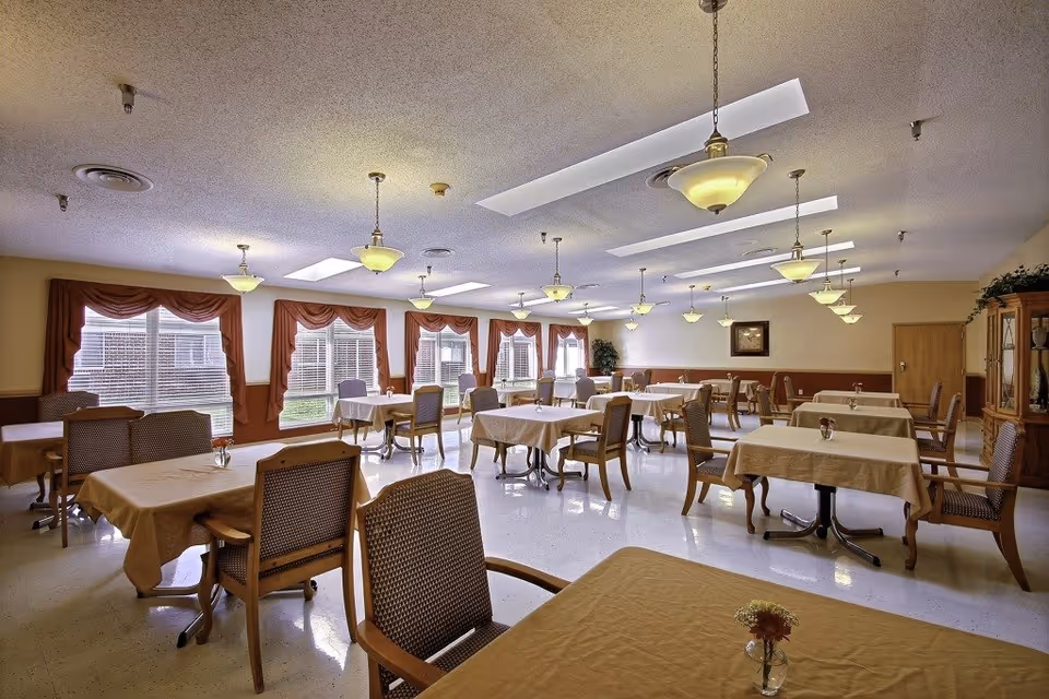 Bright dining hall with multiple tables, chairs, and red drapes