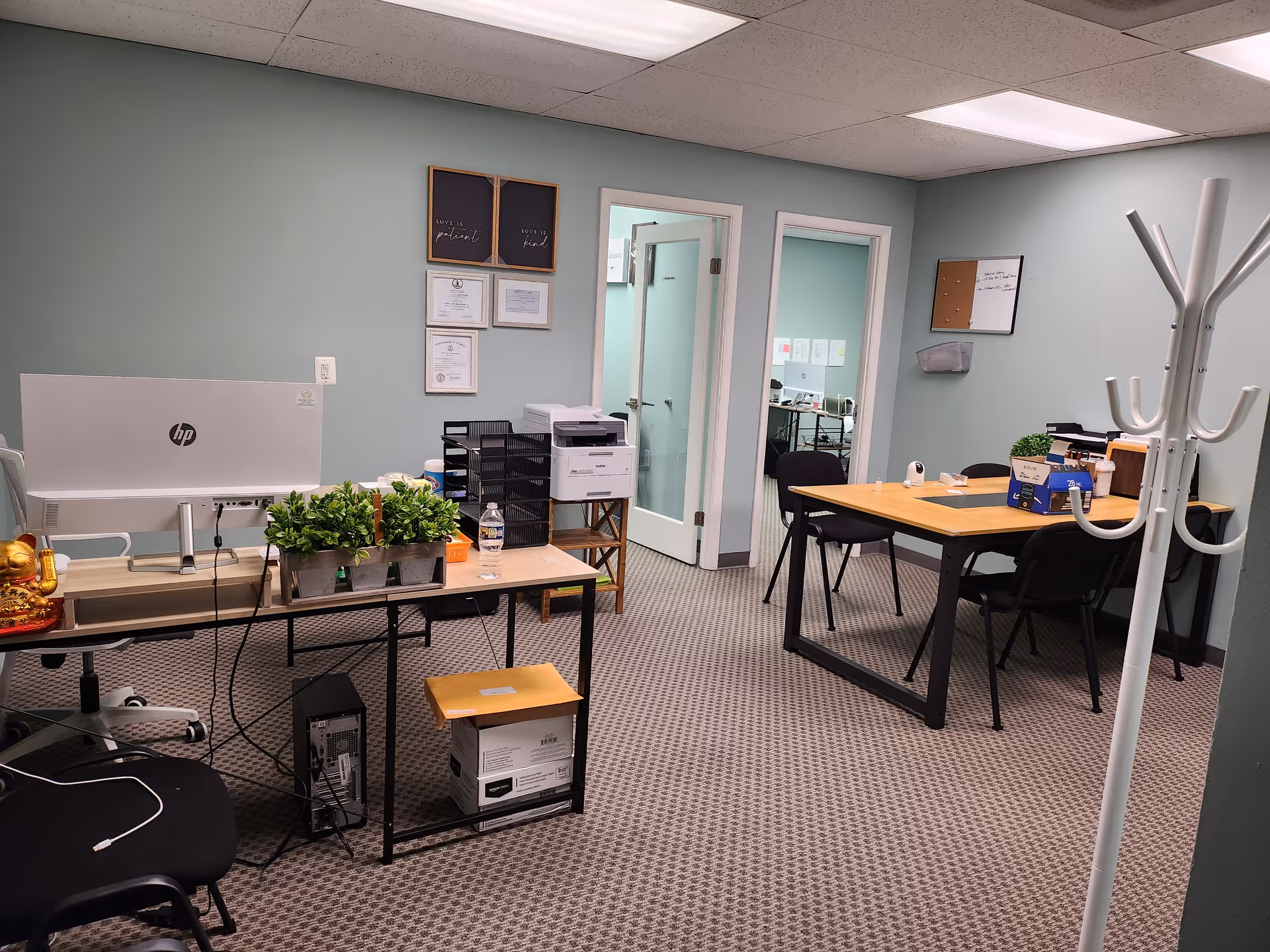 Office workspace in a senior care facility with computer, printer, plants, and tables.