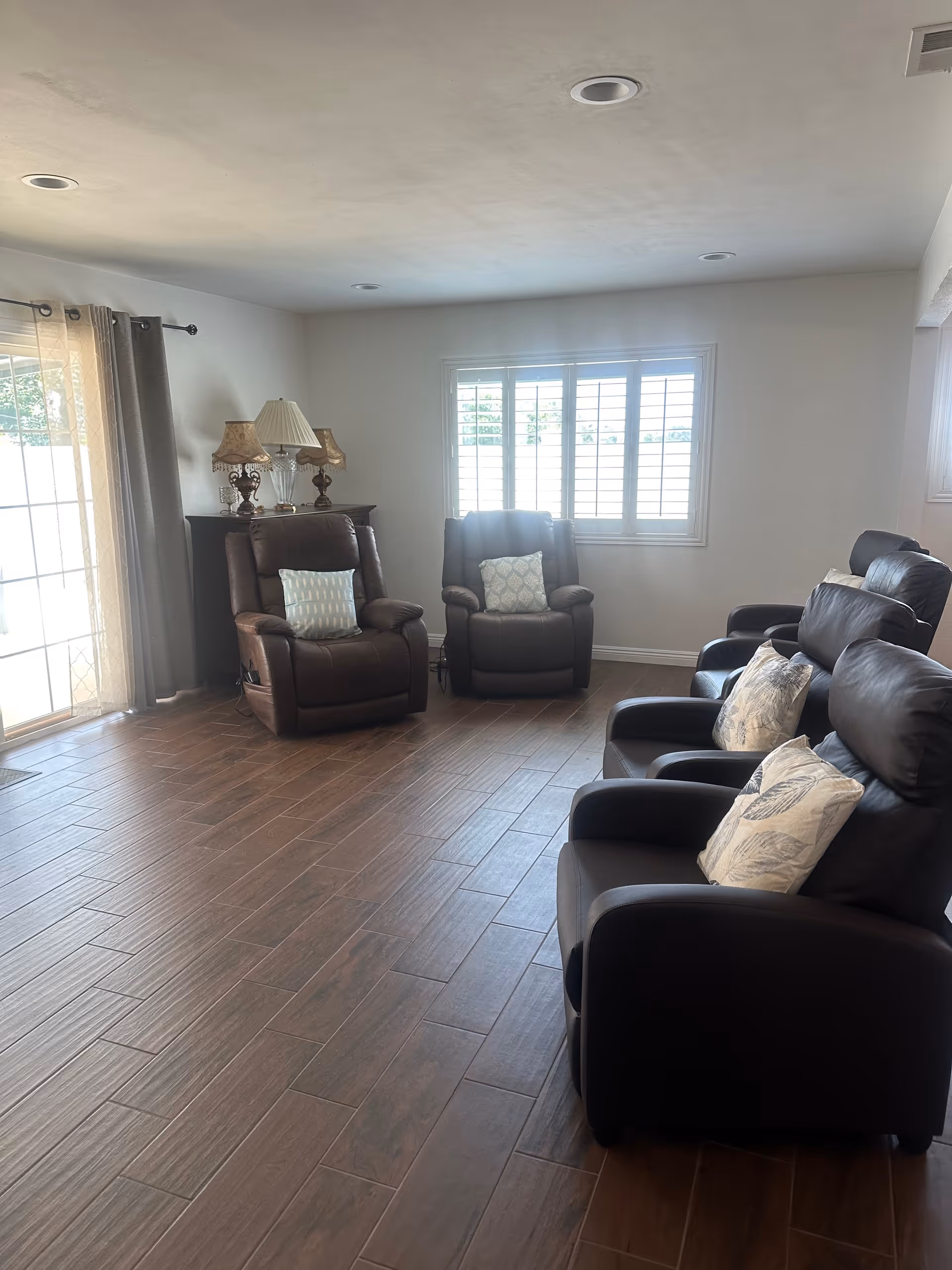 Spacious living room with leather recliners, cushions, and a window.
