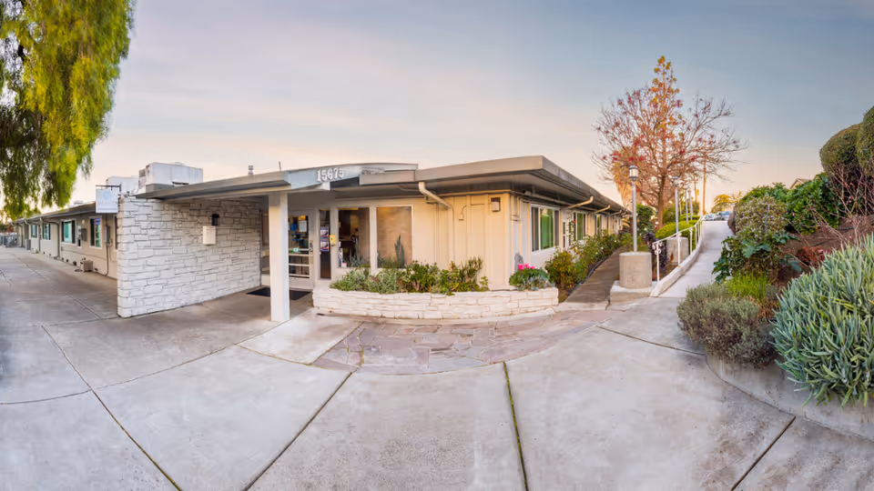 Single-story senior living facility exterior with front entrance and landscaped walkway.