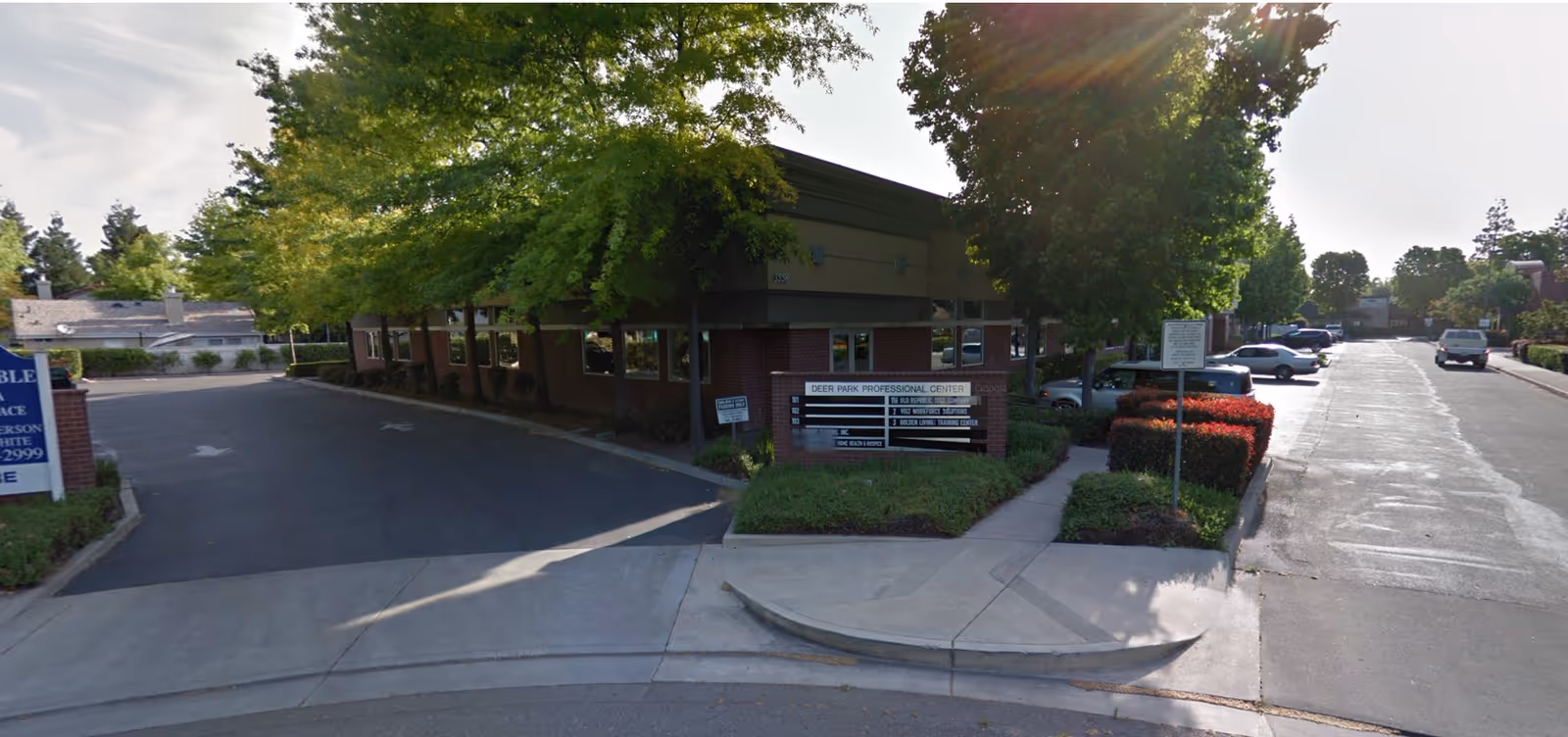 Exterior view of a low-rise medical office building with driveway, signage, and parking.