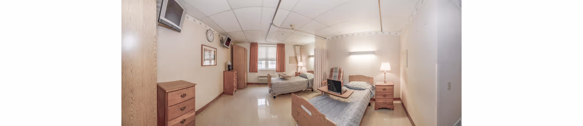 Panoramic view of a shared senior living bedroom with two beds, dressers, and nightstands.