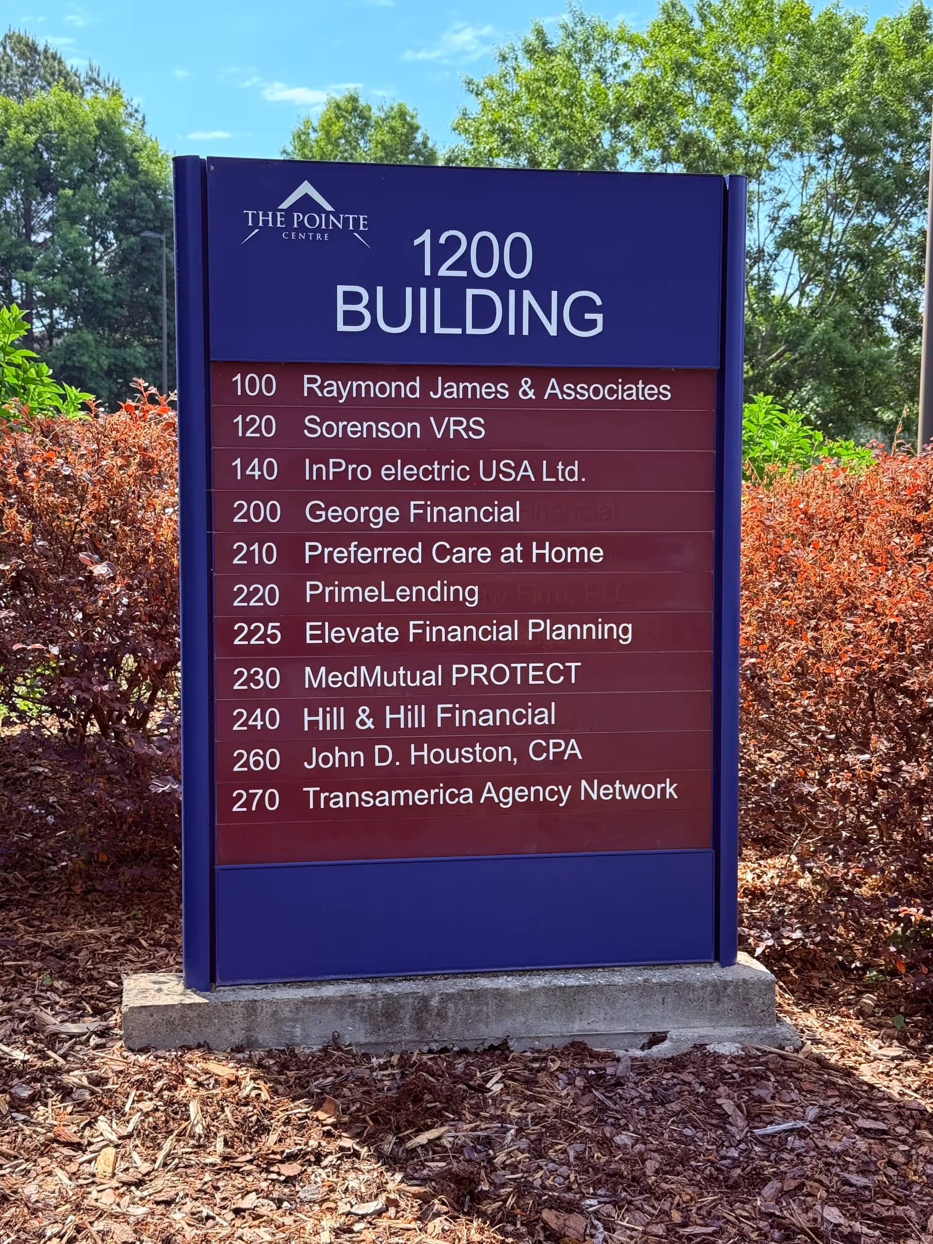 Purple outdoor sign listing tenants, including Preferred Care at Home, with landscaping.