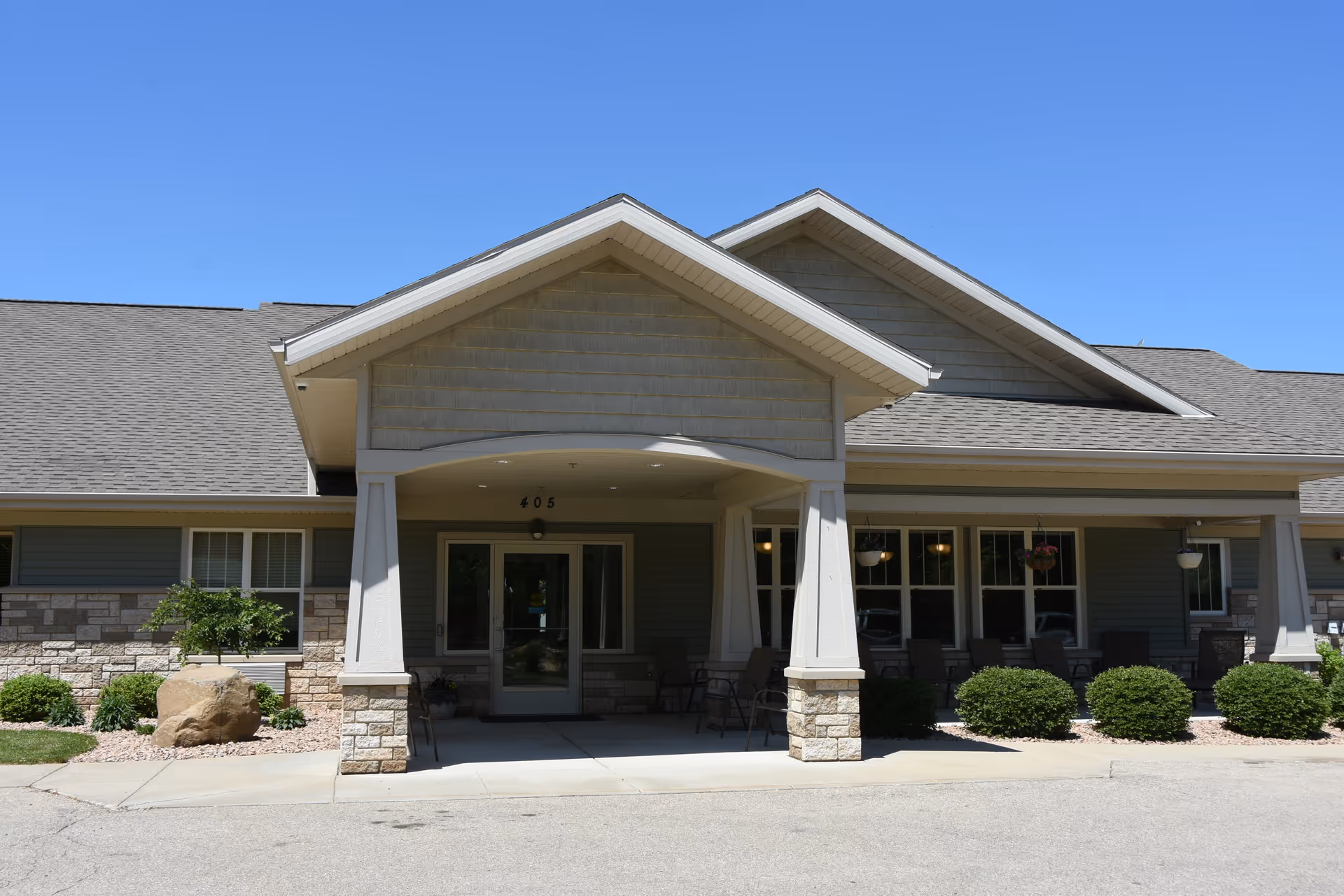 Front view of a single-story memory care facility with a covered entrance and stone accents.
