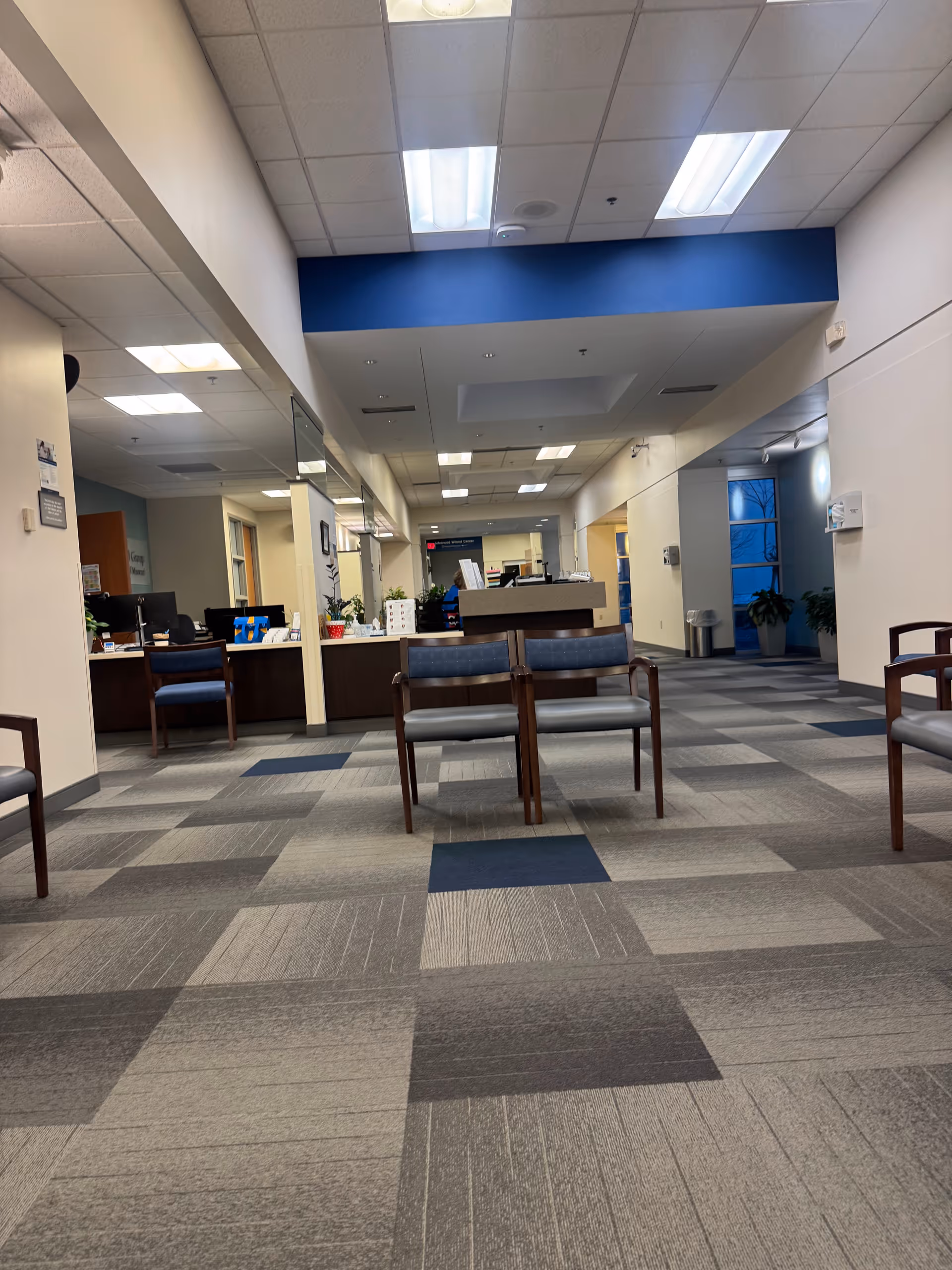 Indoor lobby with a reception desk, chairs, and a blue-accented ceiling.