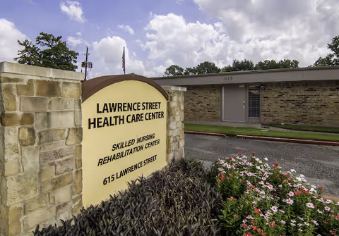 Exterior front of Lawrence Street Health Care Center with sign and landscaped bushes