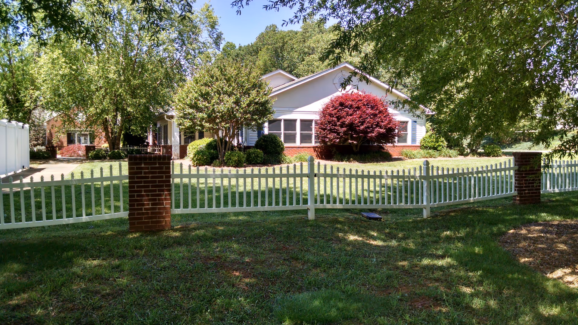 Front view of Mocksville Senior Living with white picket fence and manicured lawn.