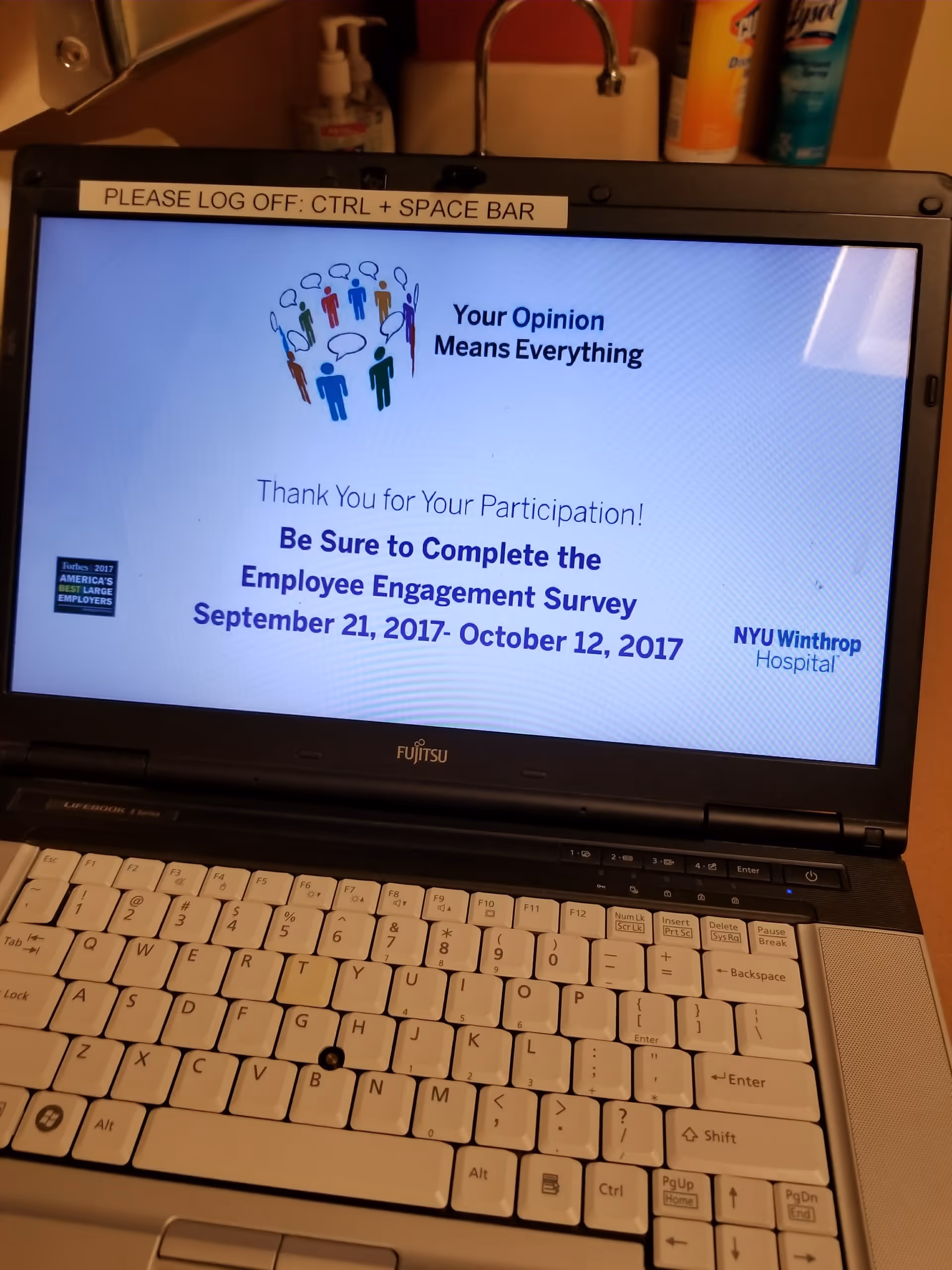 Laptop on a desk displays an employee engagement survey slide on screen.