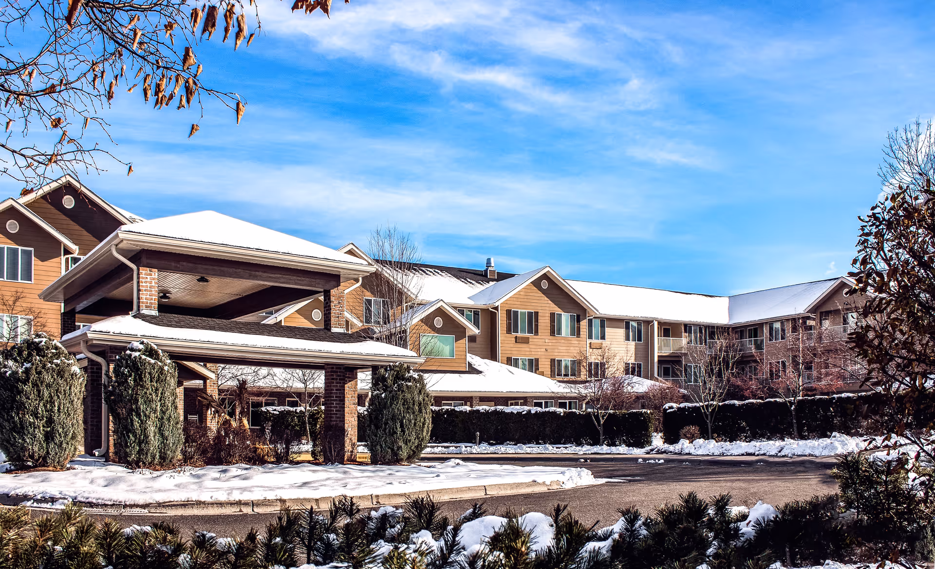 Snow-covered Lodge at White Bear exterior with a covered entrance and tidy landscaping.