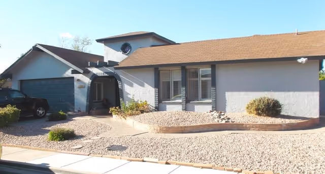 Front exterior of a single-story building with a driveway and desert landscaping.