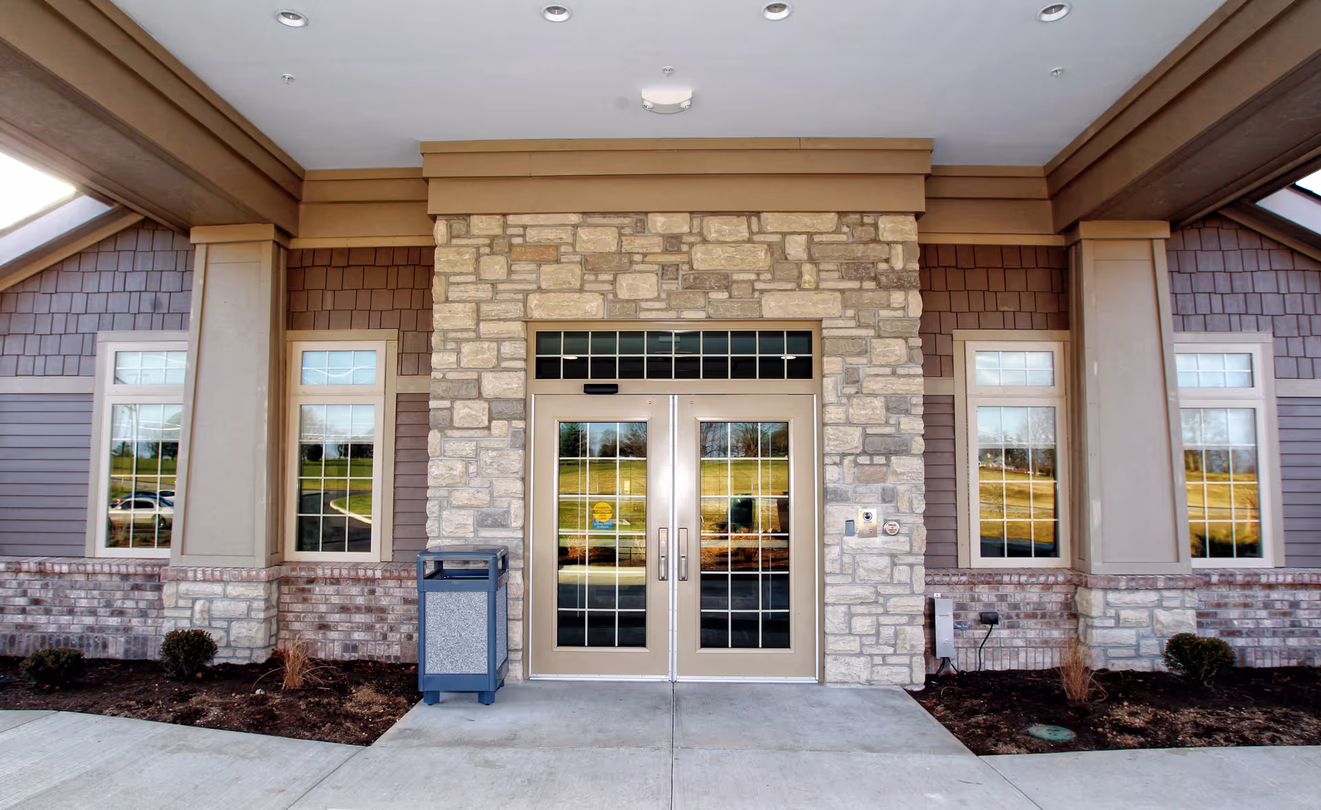 Exterior entrance of a senior living facility with stone facade and double glass doors.