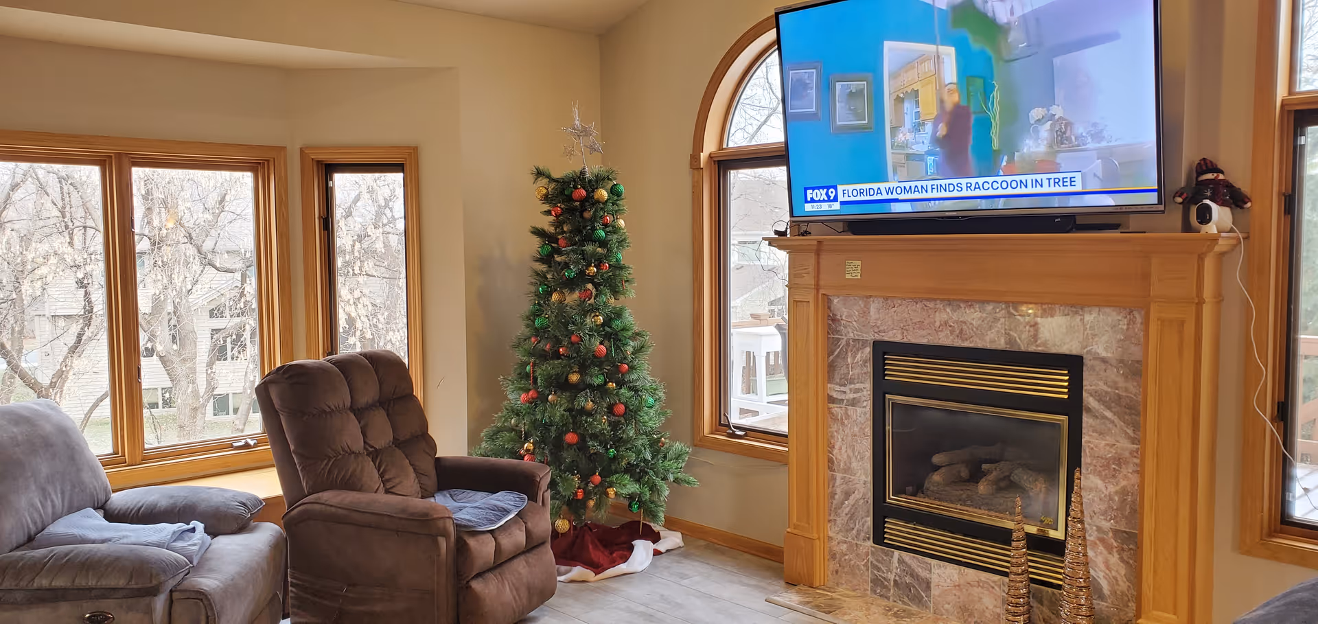 Cozy Brookview Cottage living room with a sofa, recliner, Christmas tree, and fireplace.