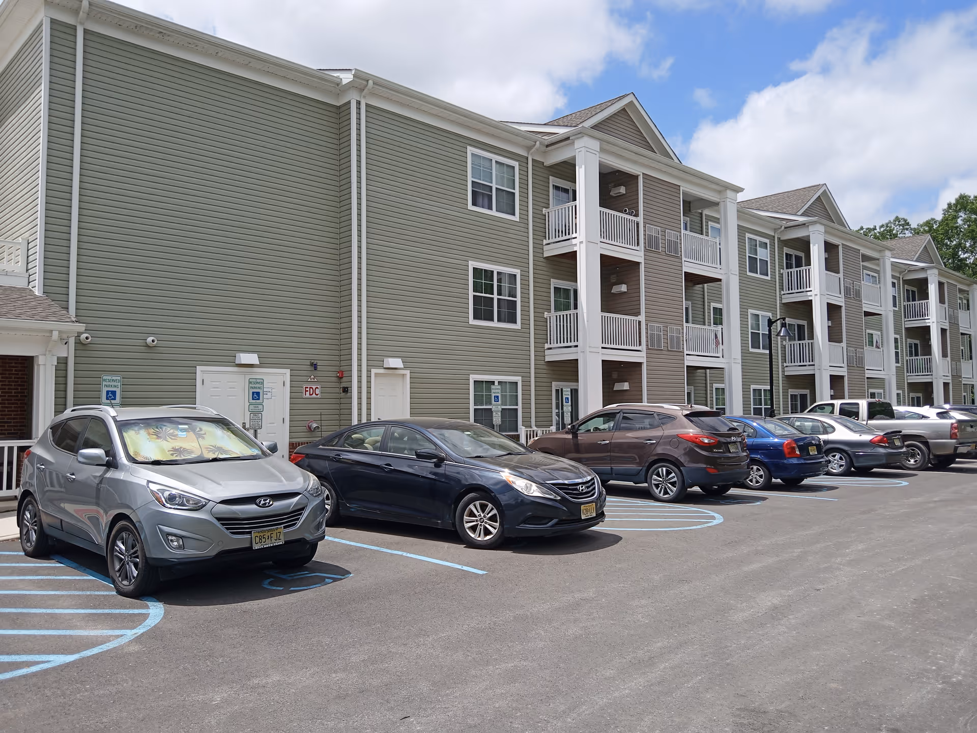 Exterior view of Waterfront Village with multi-story balconies and a row of parked cars.