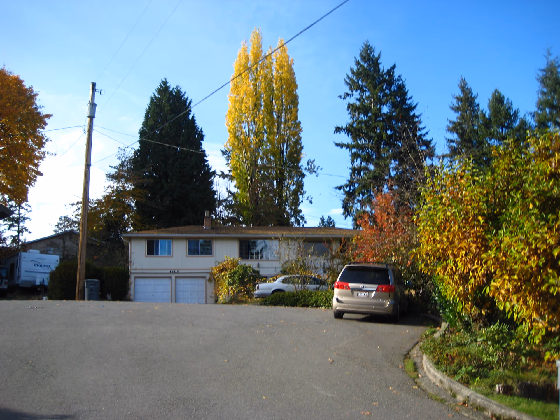 Front exterior of Grace Elderly Care facility, a two-story residence with garages, trees, and parked cars.