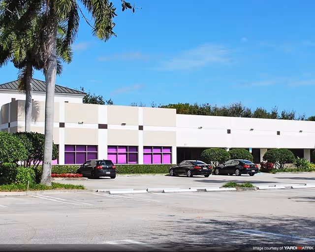 Exterior view of a white building with purple windows and parked cars.