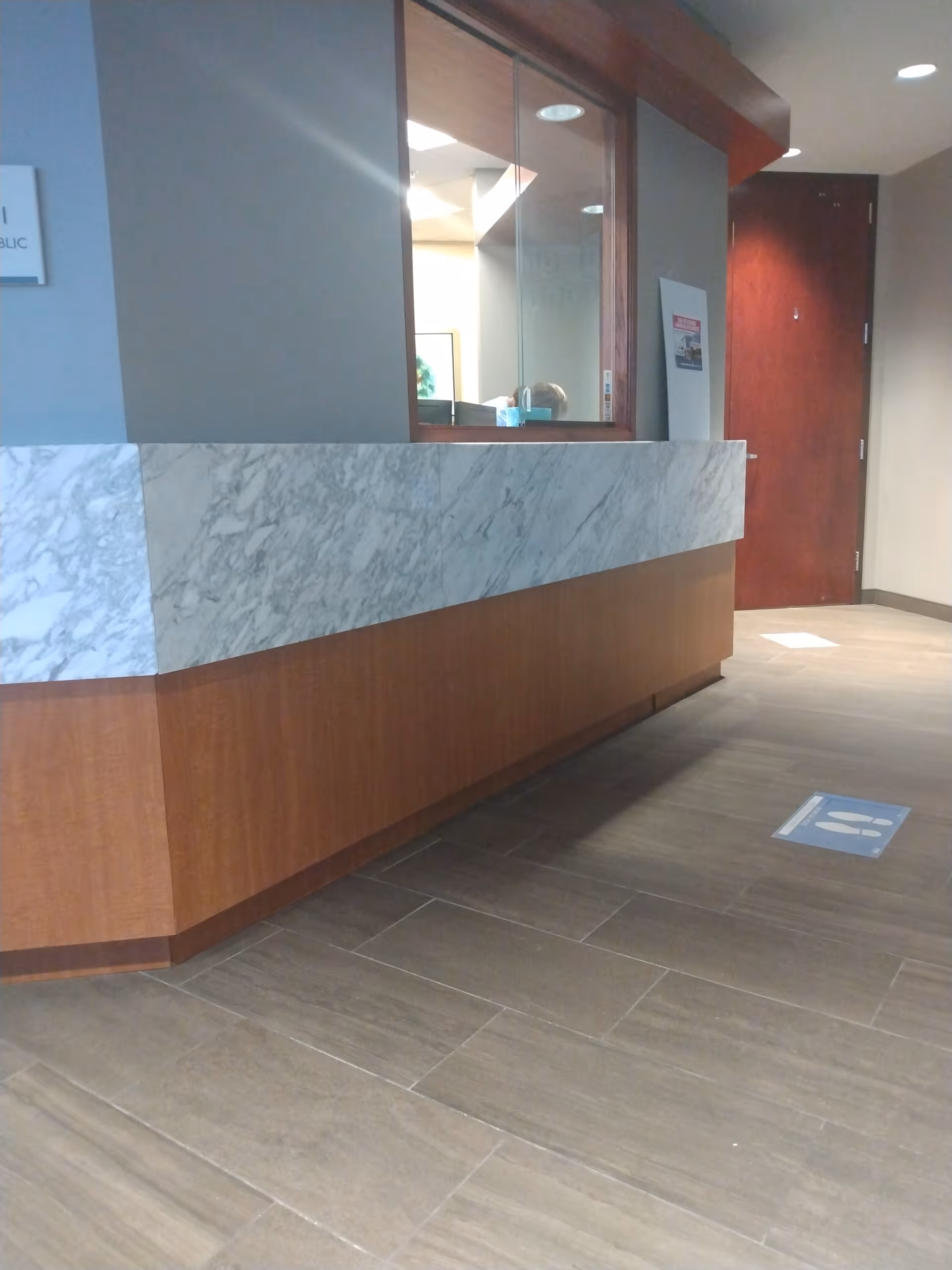 Interior reception desk with marble counter, wood paneling, and tiled floor.