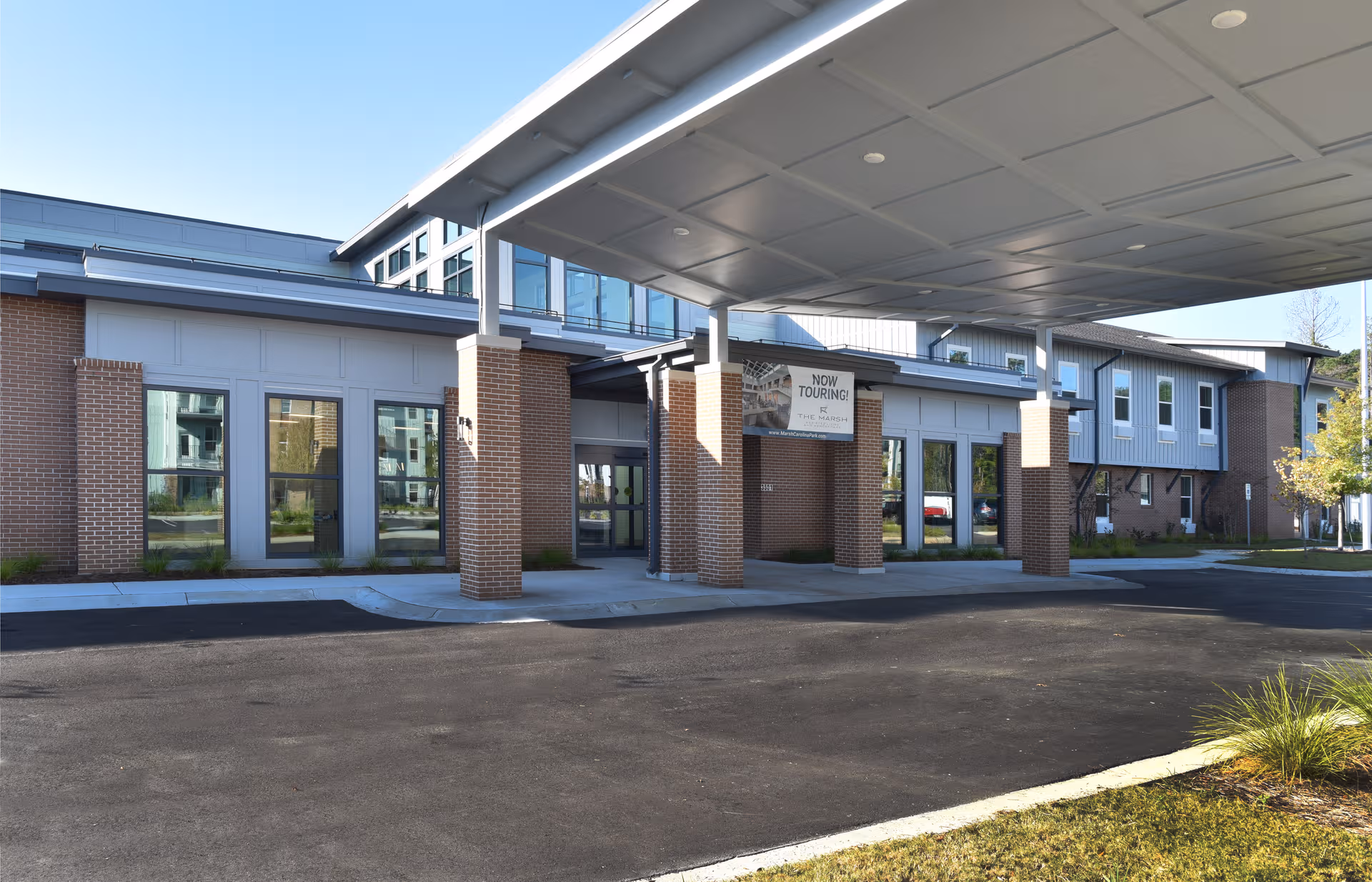 Exterior view of The Marsh at Carolina Park entrance with brick columns and glass doors.
