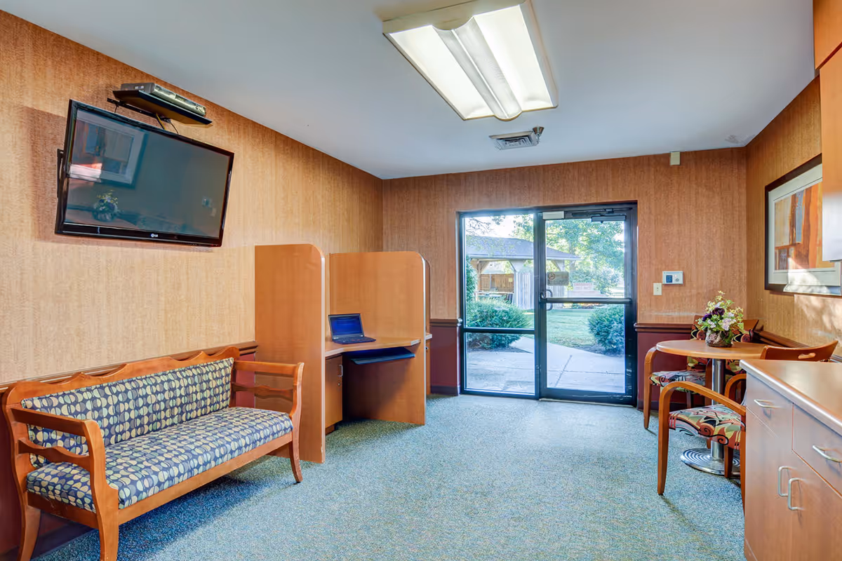 Interior lounge area with a patterned sofa, divider, desk, TV, and glass door to outside