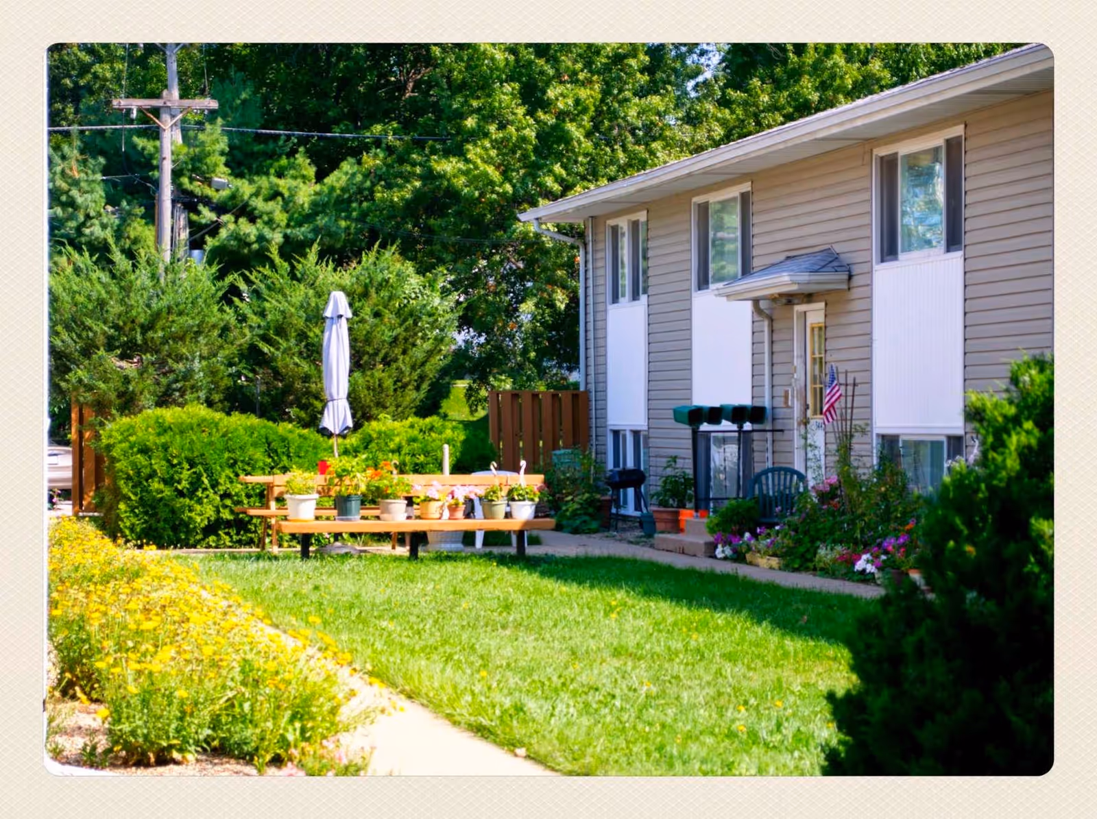 Exterior of Evergreen Estates I showing a lawn, potted plants, and outdoor seating.