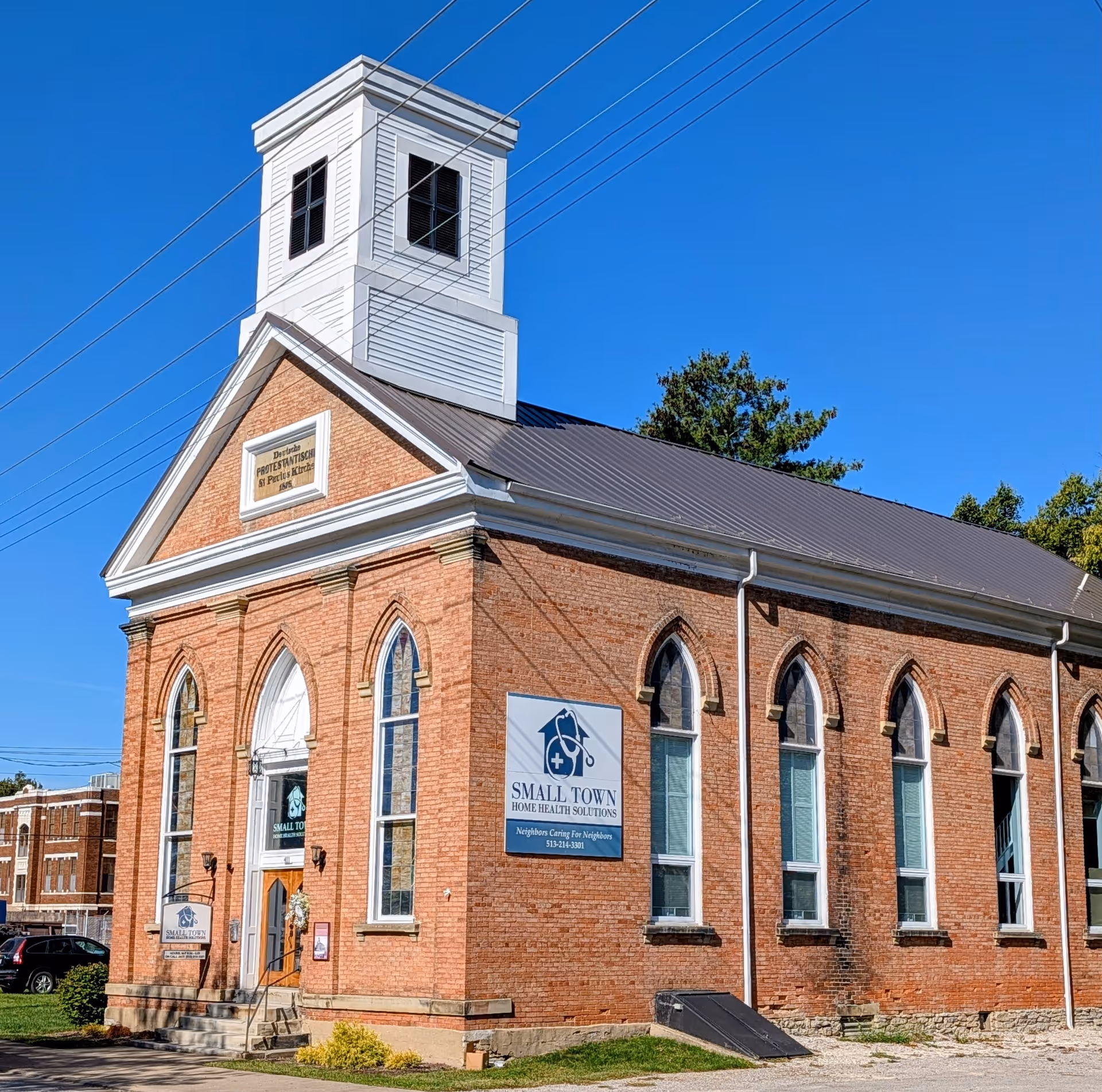 Brick building with a white steeple and Small Town Home Health Solutions sign.