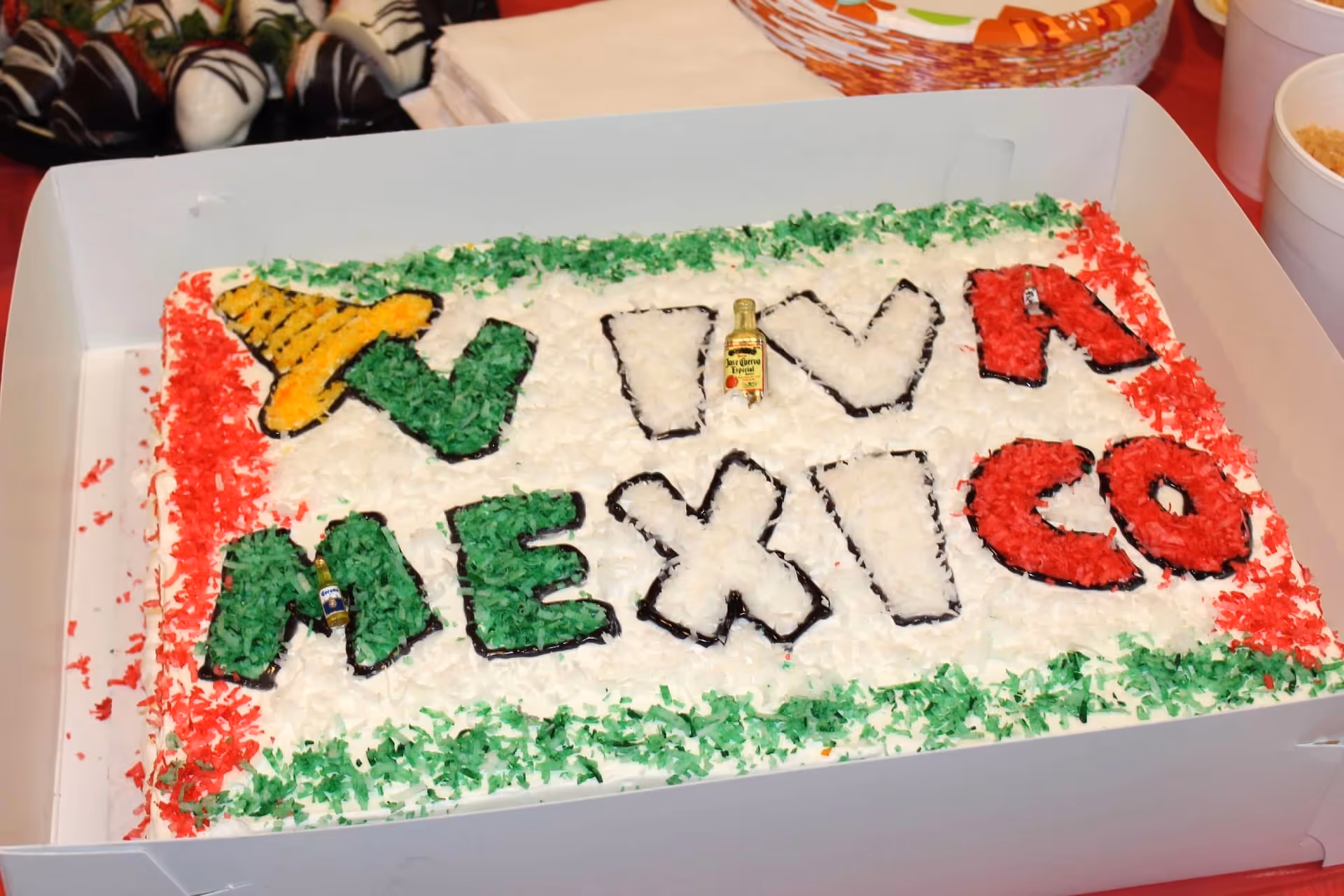 A large Mexican-themed cake with green, white, and red decorations on a table.