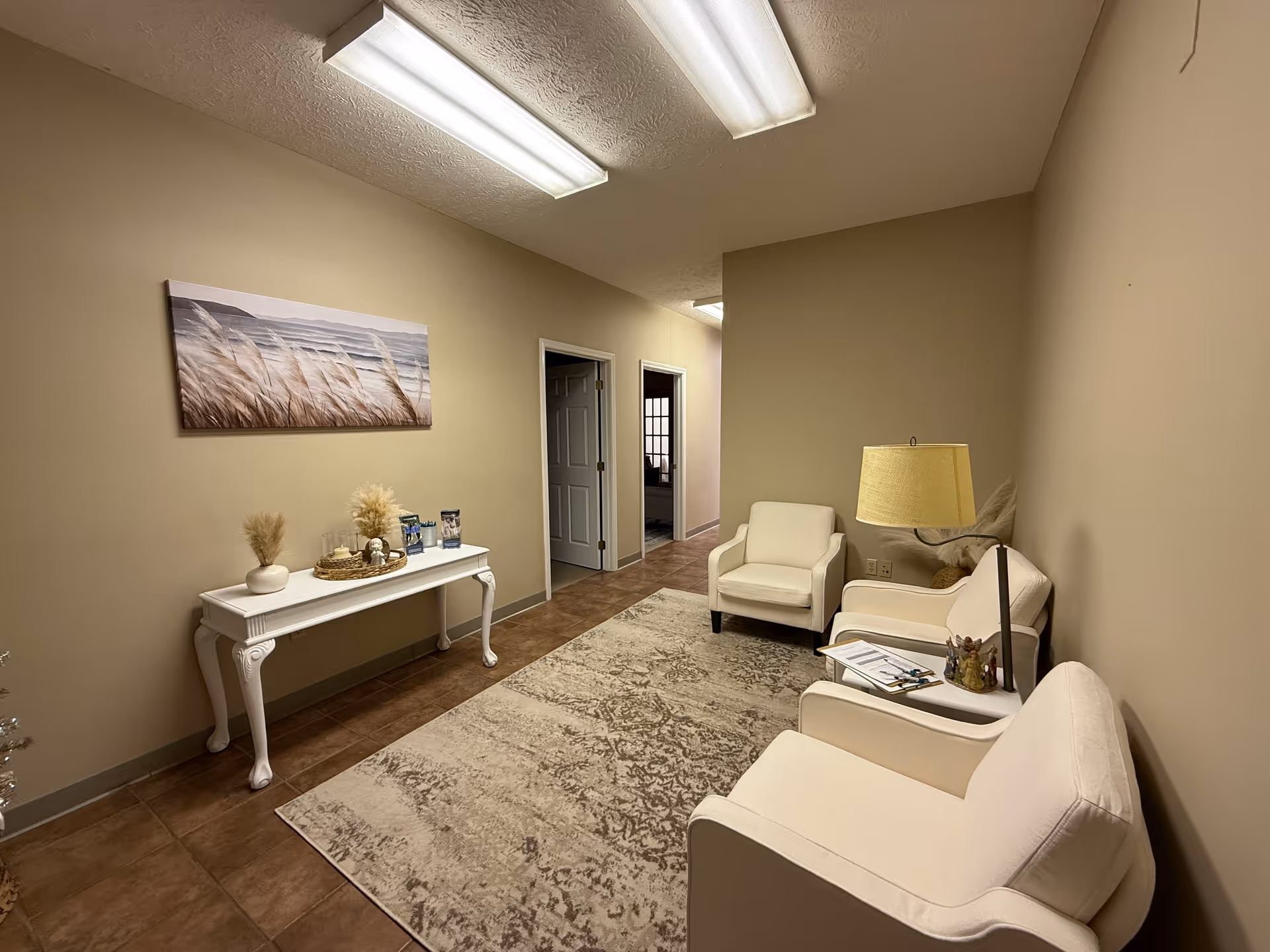 Neutral lobby seating area with white furniture, rug, and a decorative console table.