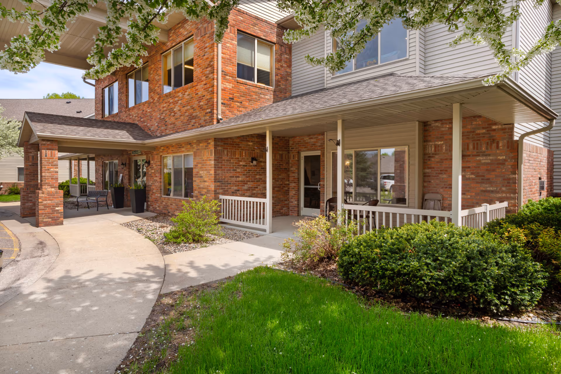 Exterior view of Mankato Lodge Senior Living entrance with brick facade, porch, and landscaping.