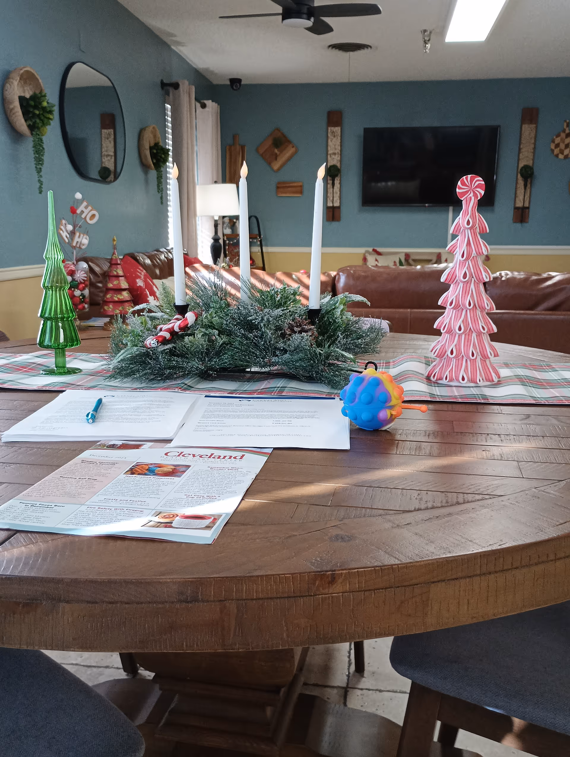 Round wooden table with holiday centerpiece and magazines in a blue-walled living room.