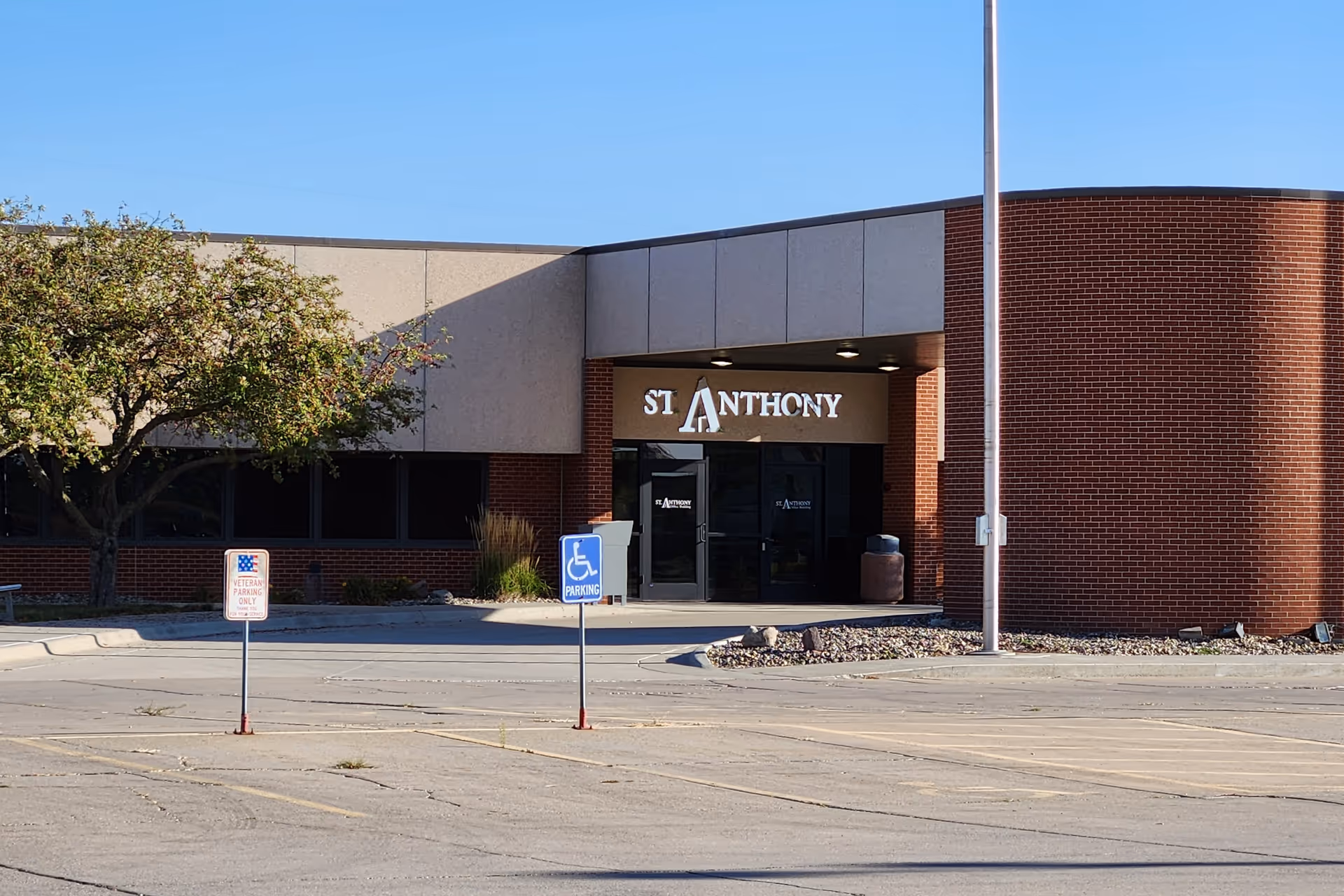 Exterior view of St. Anthony entrance with parking lot and handicap signs.