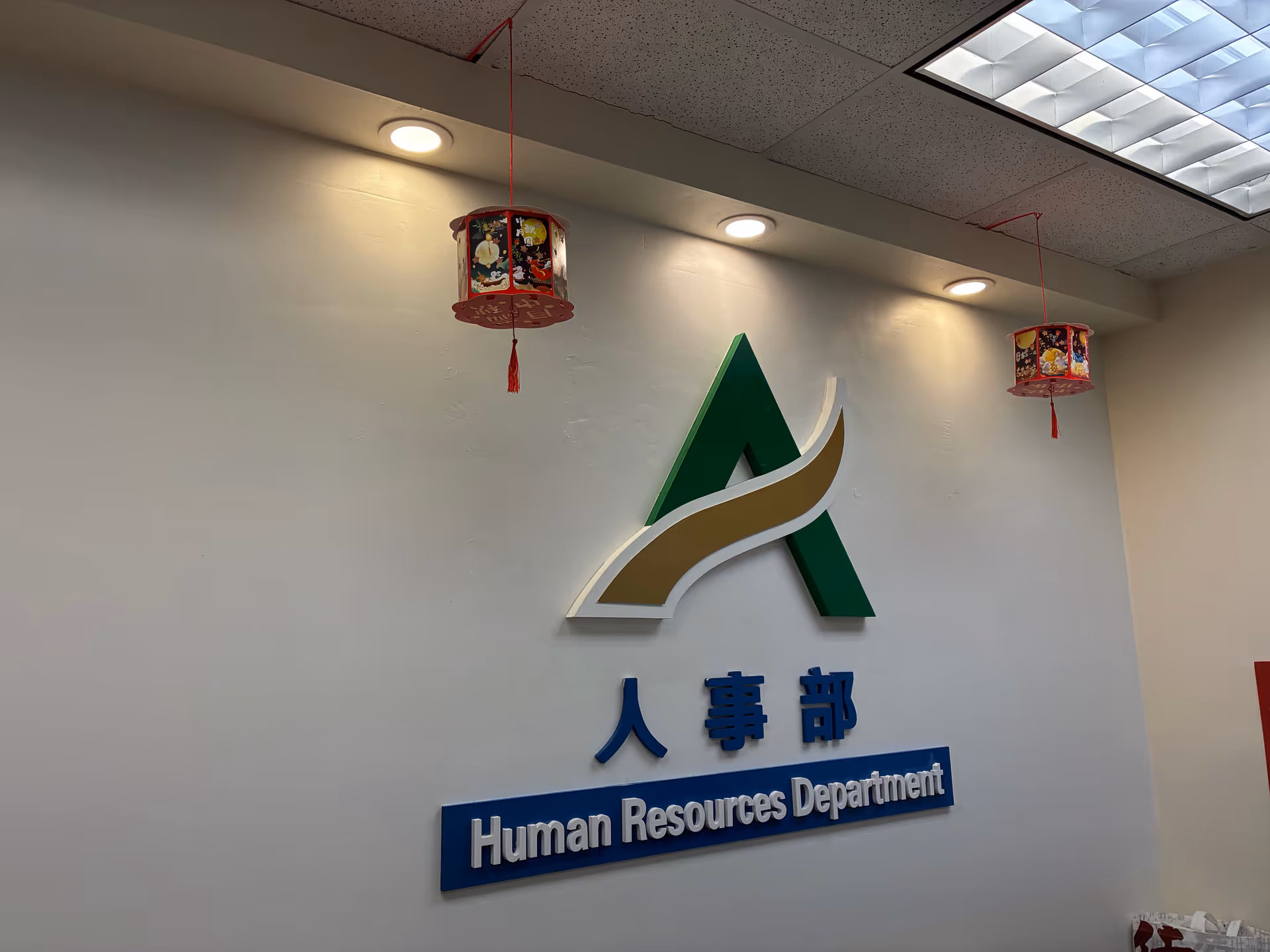 Interior wall featuring a logo and Human Resources Department sign with ceiling lights and lanterns.