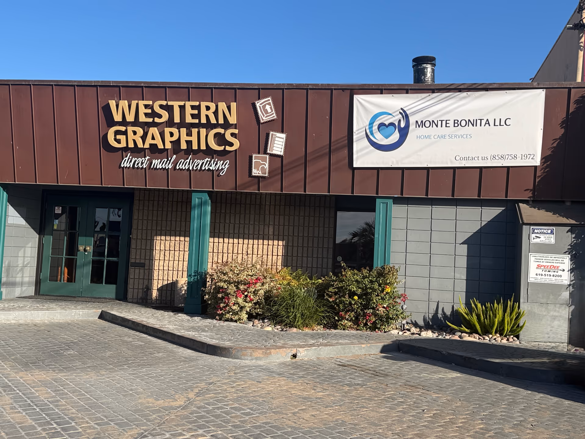 Exterior storefront with Monte Bonita LLC banner and Western Graphics sign on brown facade.