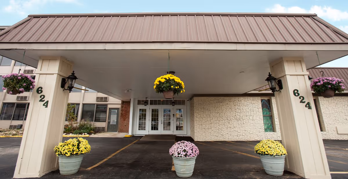 Senior Care Plaza entrance with a covered drop-off and flower pots.