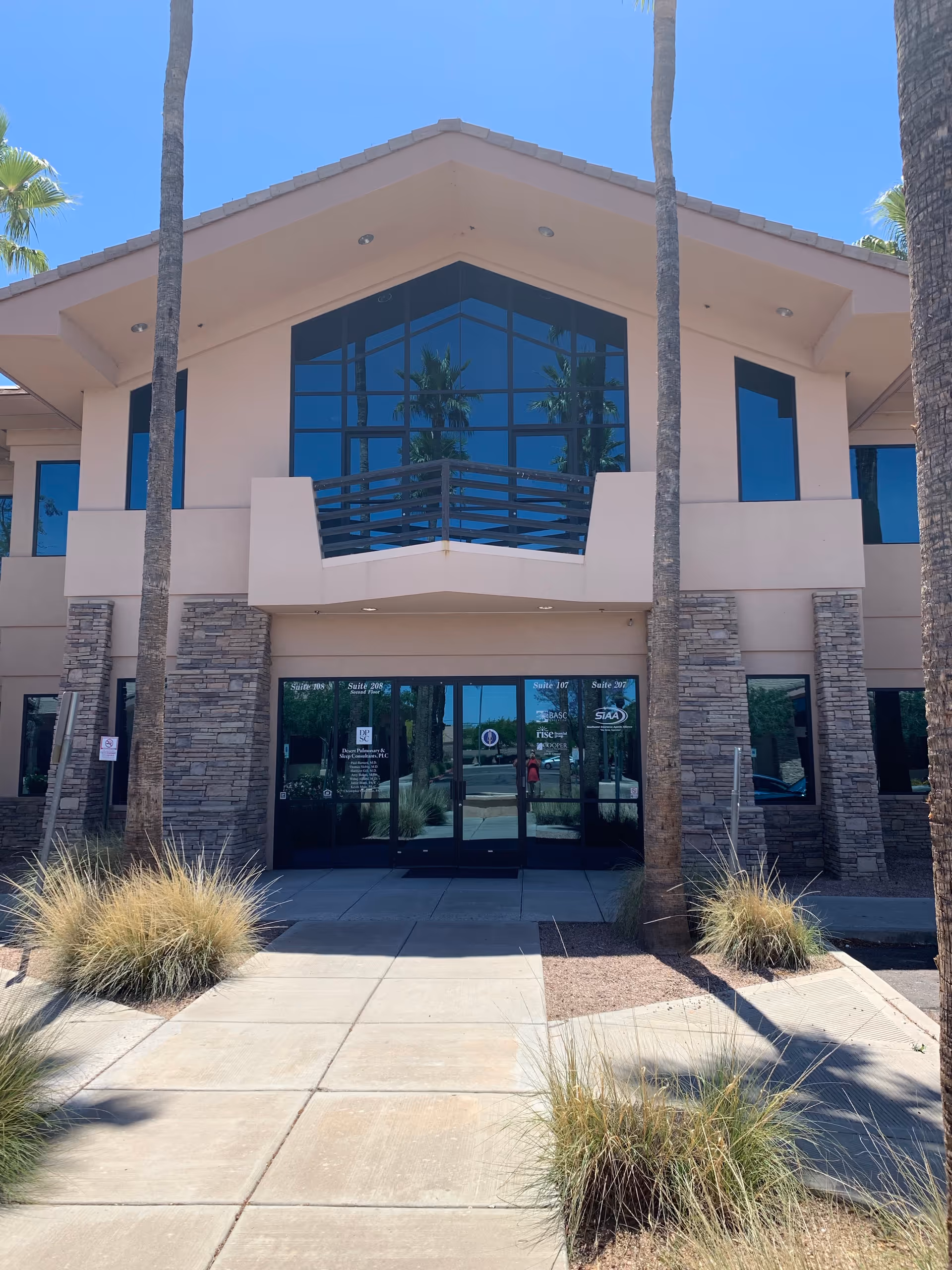 Front entrance of Like Family Home Care facility with glass doors and palm trees.