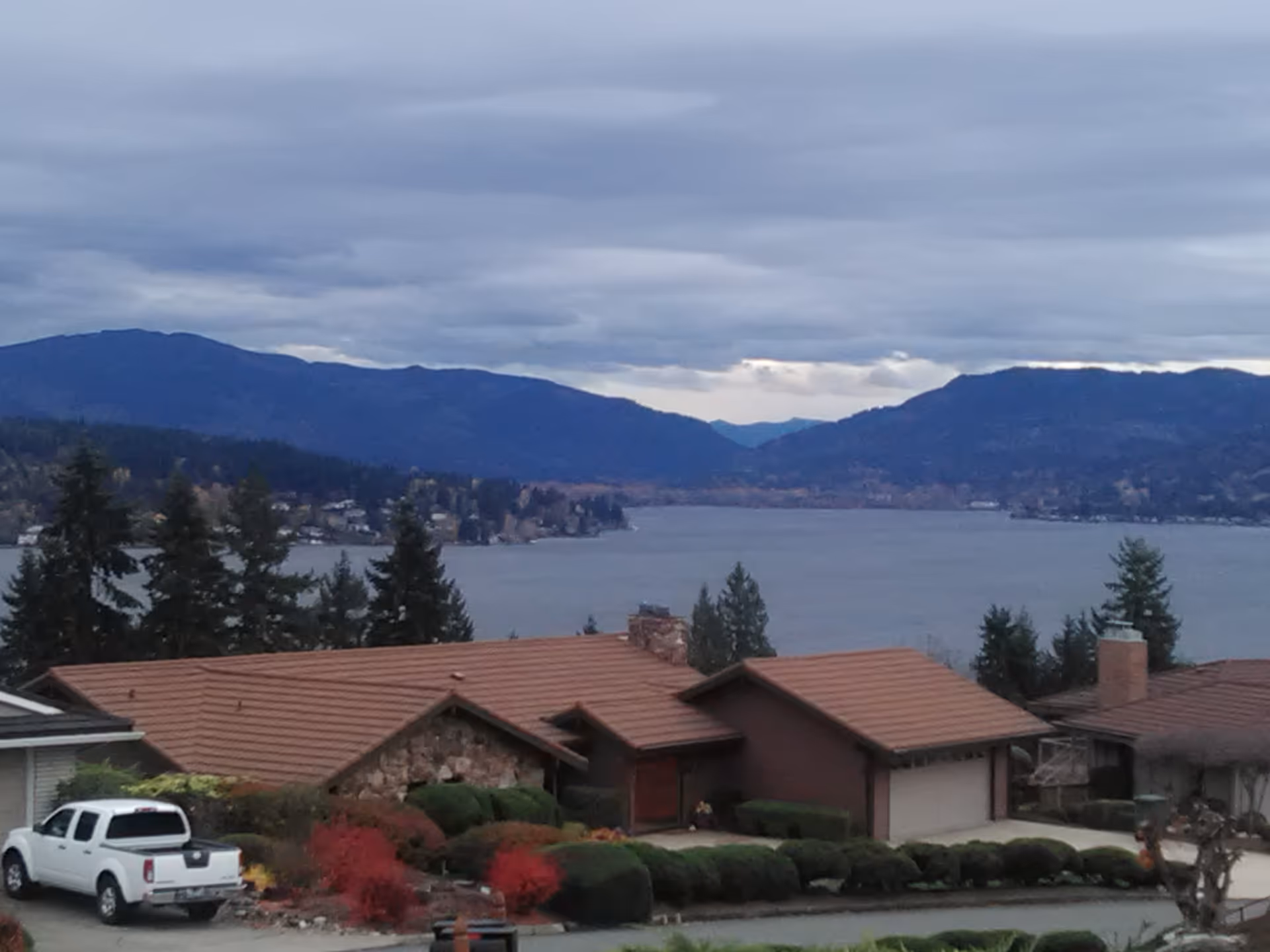 Exterior view of suburban homes along a lake with distant mountains and cloudy sky