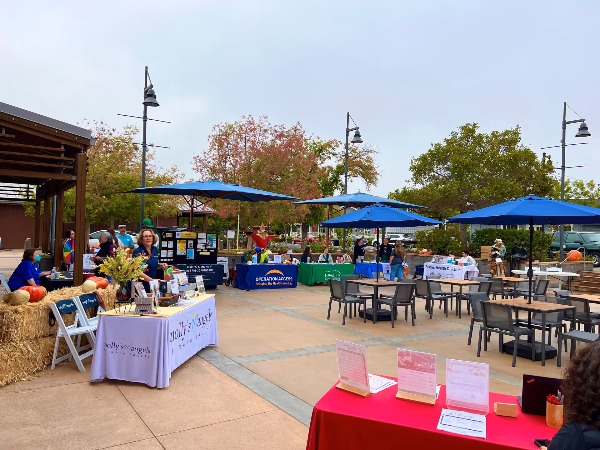 Outdoor courtyard at Senior Helpers Napa with blue umbrellas and vendor booths.