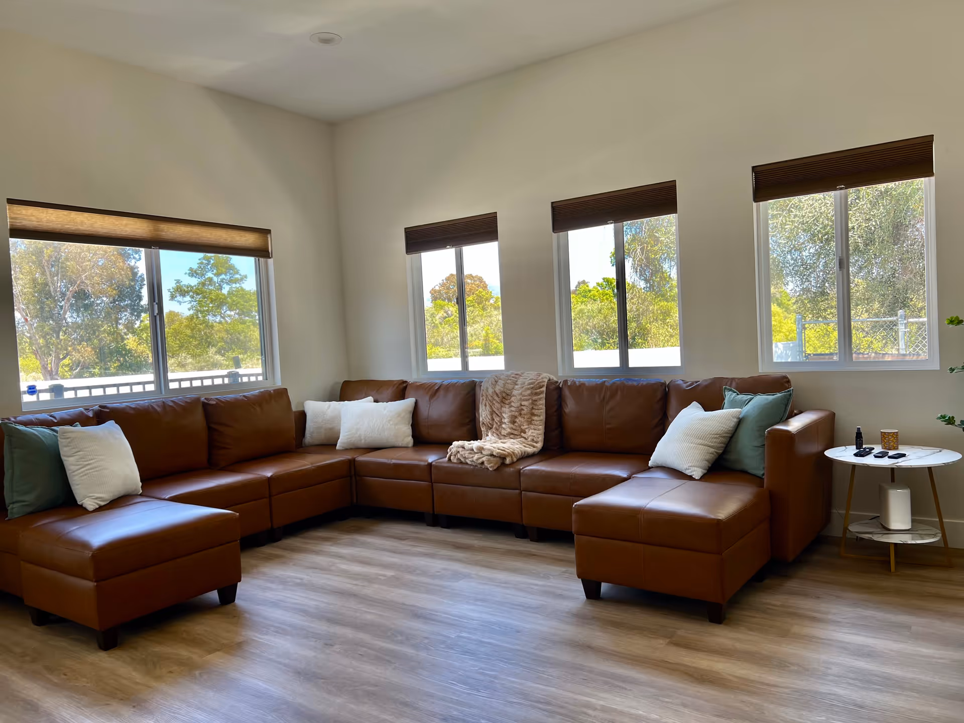 Spacious living room with brown sectional sofa, pillows, and large windows.