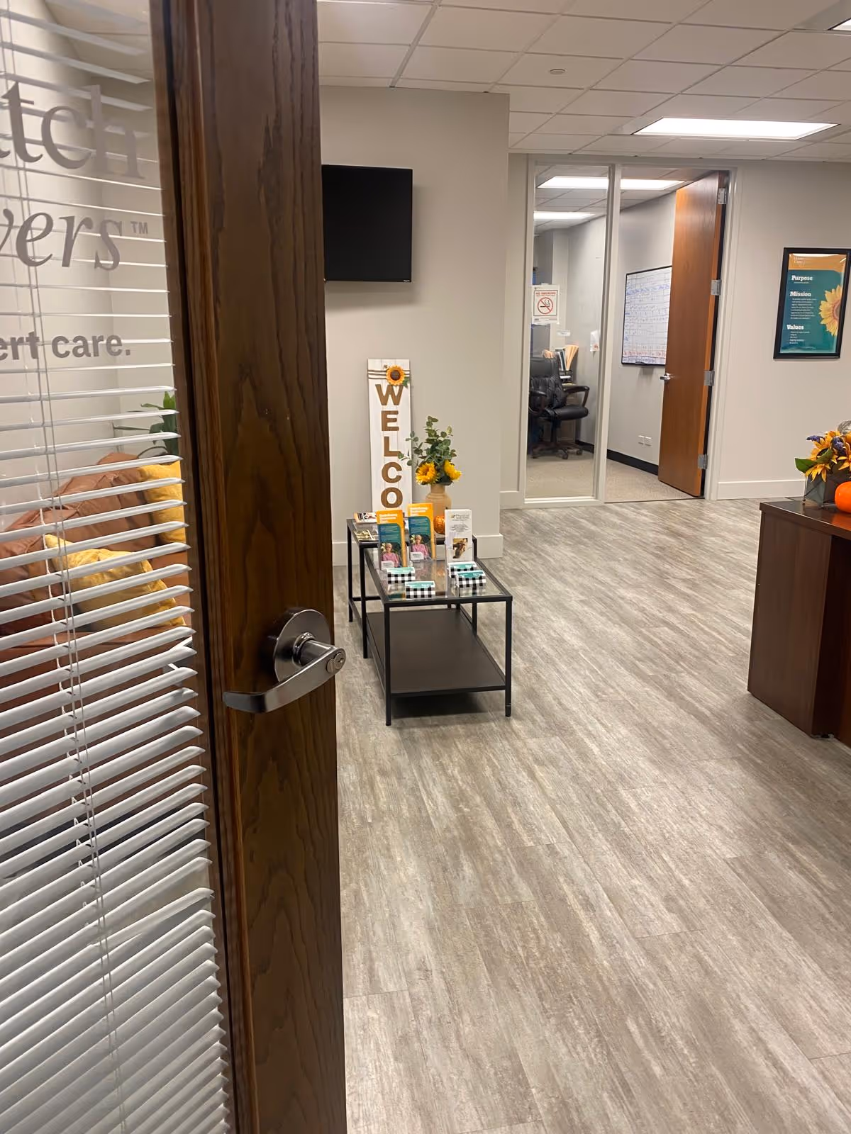 Lobby area with a welcome sign, brochure table, plants, and seating.