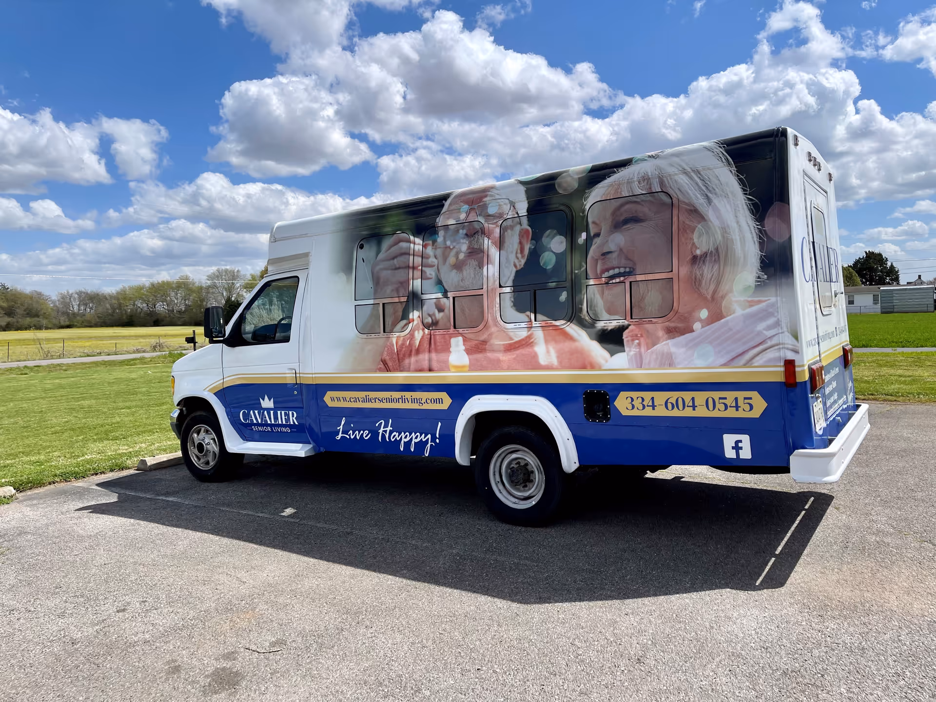 White and blue senior transportation van with large graphics parked in a lot.