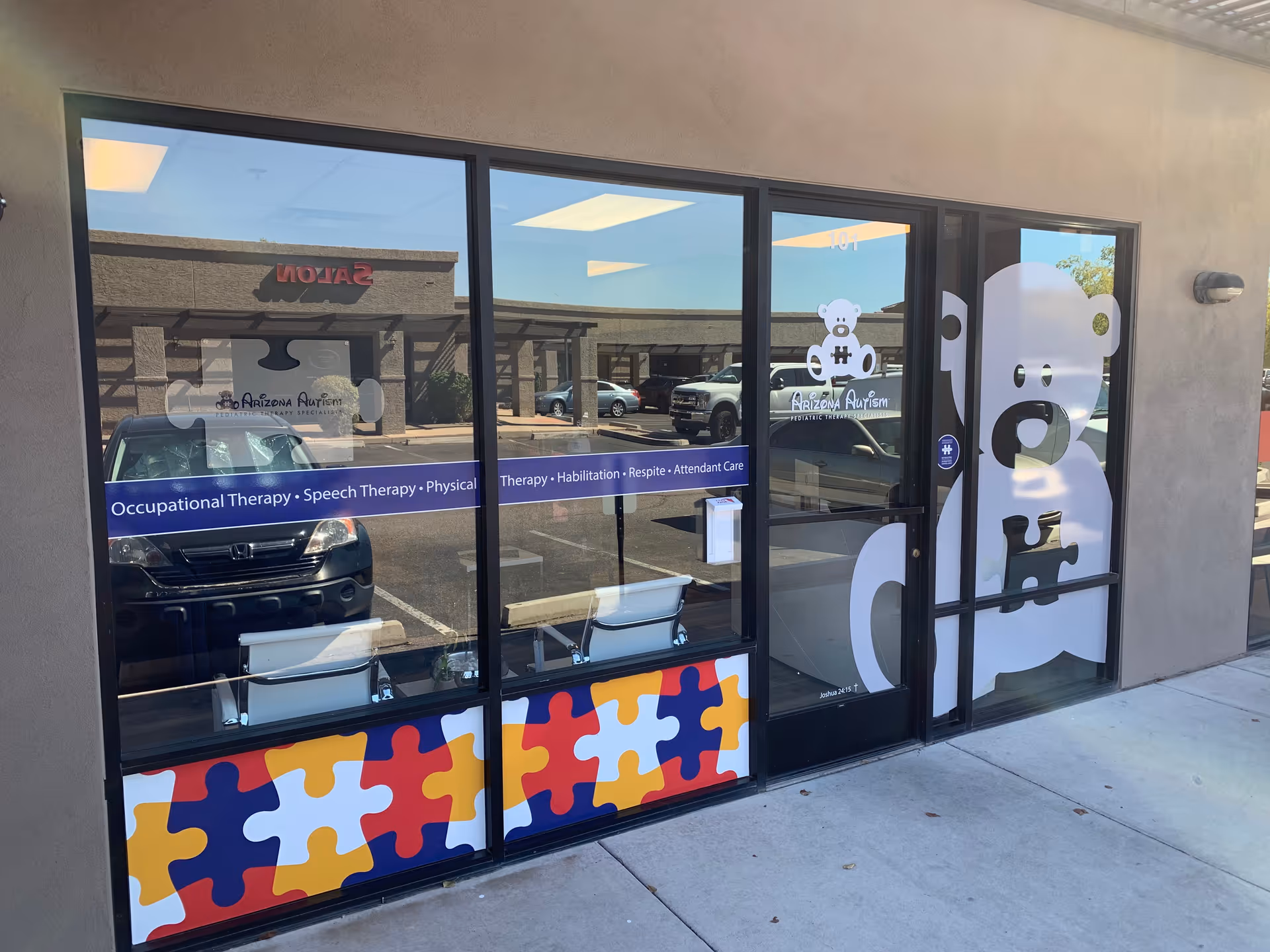 Exterior storefront of Arizona Autism with glass doors and colorful puzzle artwork.