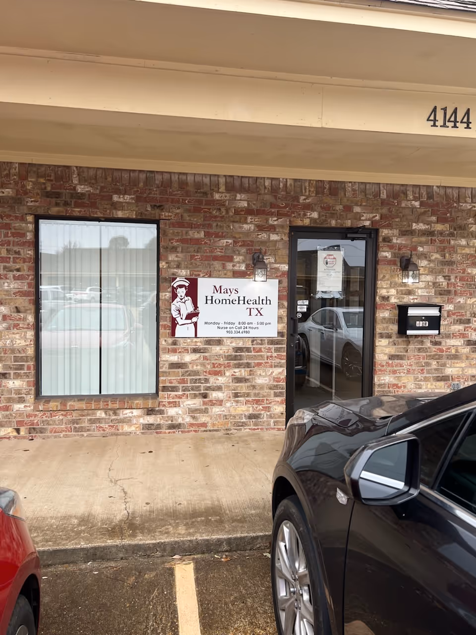 Brick building exterior with a sign for Mays HomeHealth and a glass door.