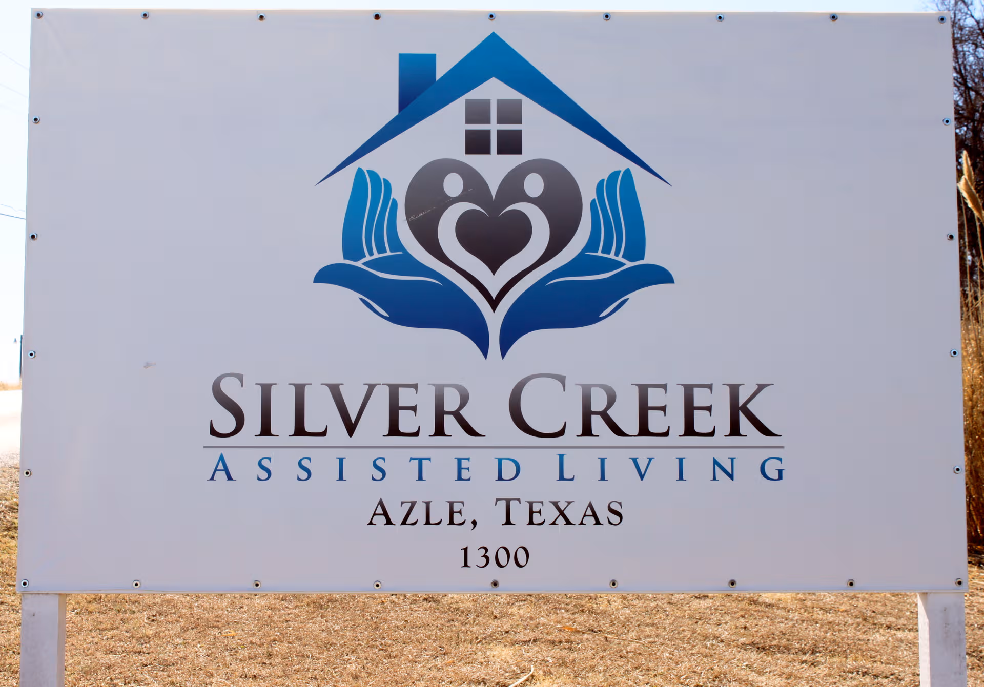 Large white exterior sign for Silver Creek Assisted Living with a blue logo.